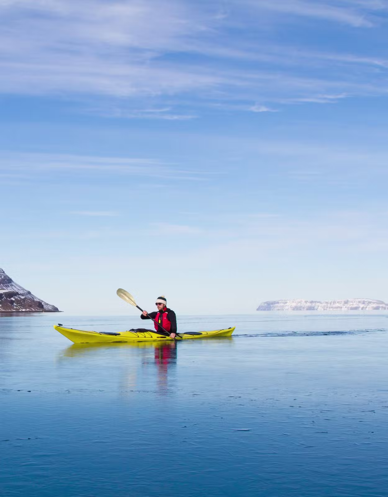 Kayakers on Ísafjarðardjúp with mountains rising around the Westfjords fjord system.