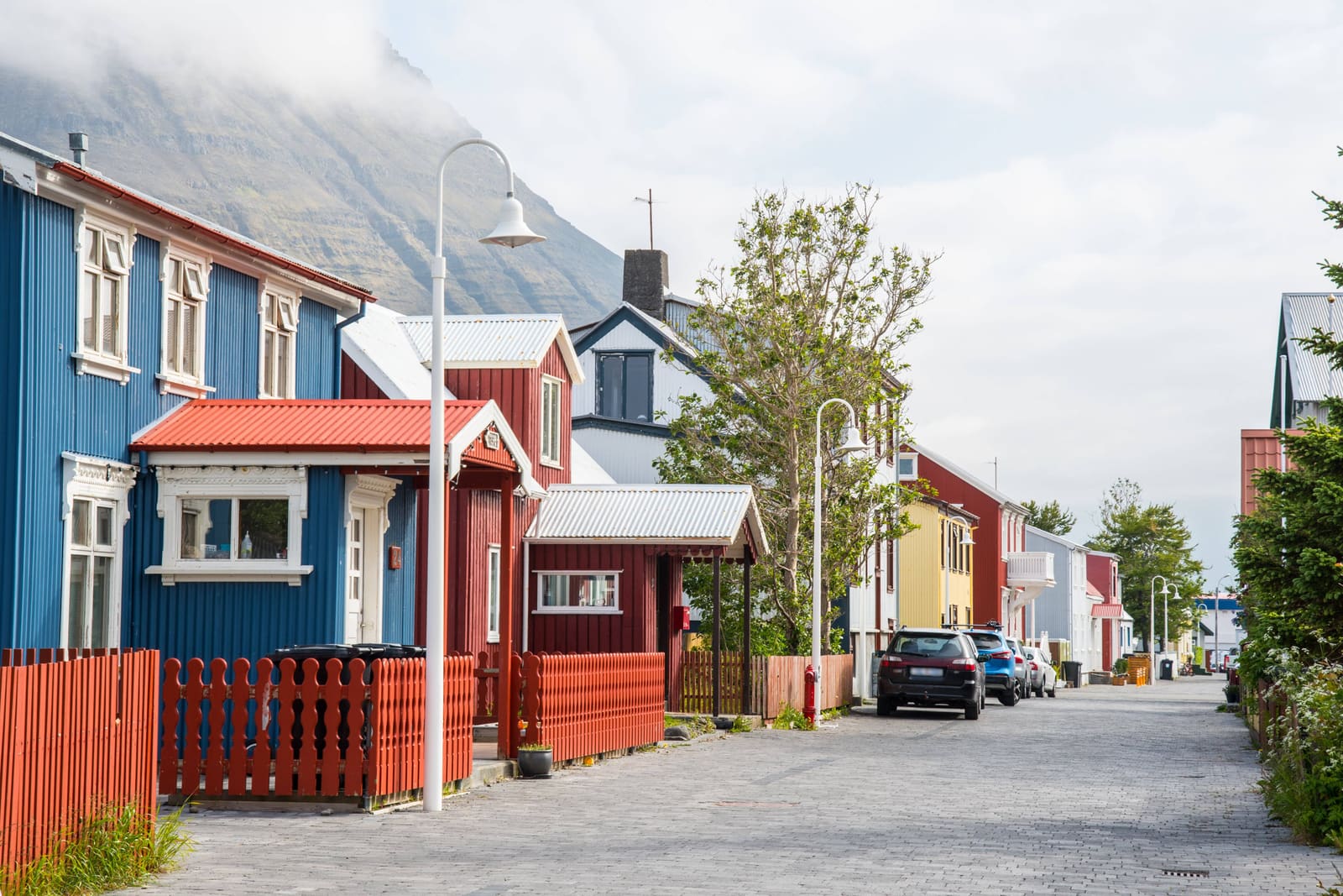 Colorful wooden houses on a quiet street in Ísafjörður with Westfjords mountains behind.