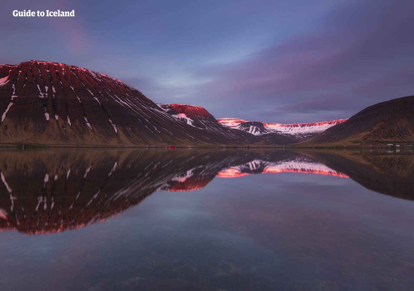 Snowy mountains reflected in still Skutulsfjörður water around Ísafjörður in the Westfjords.