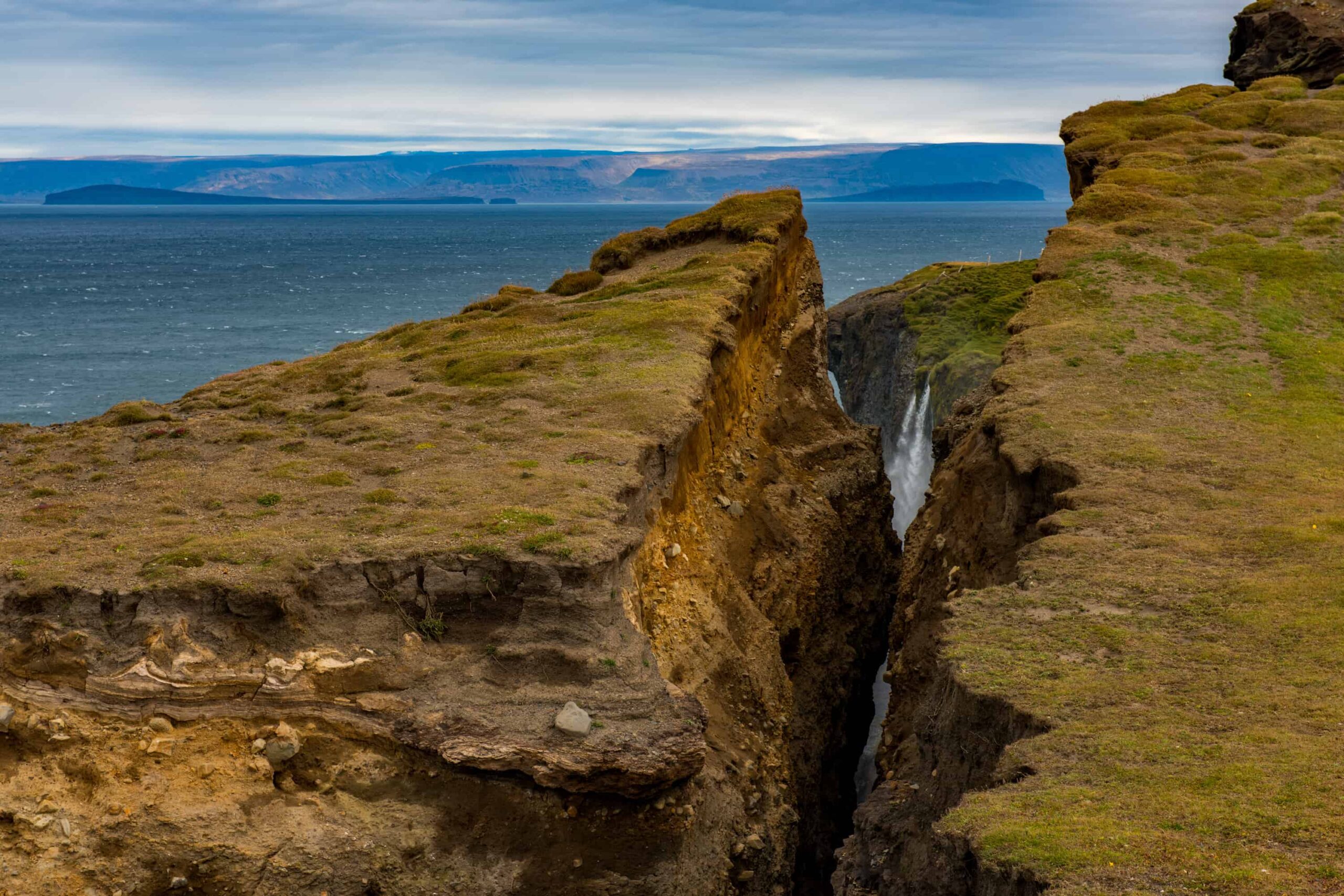 Ketubjörg waterfall dropping through a narrow sea-cliff chasm on the Skagi coast.
