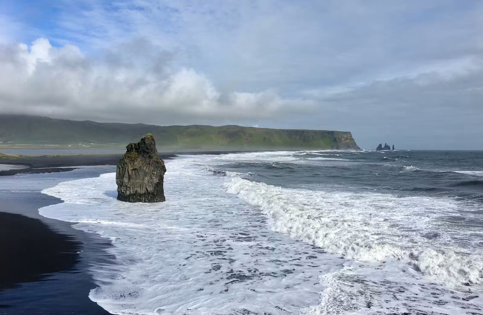 Reynisfjara black sand beach with Atlantic surf and Reynisdrangar sea stacks near Vík.