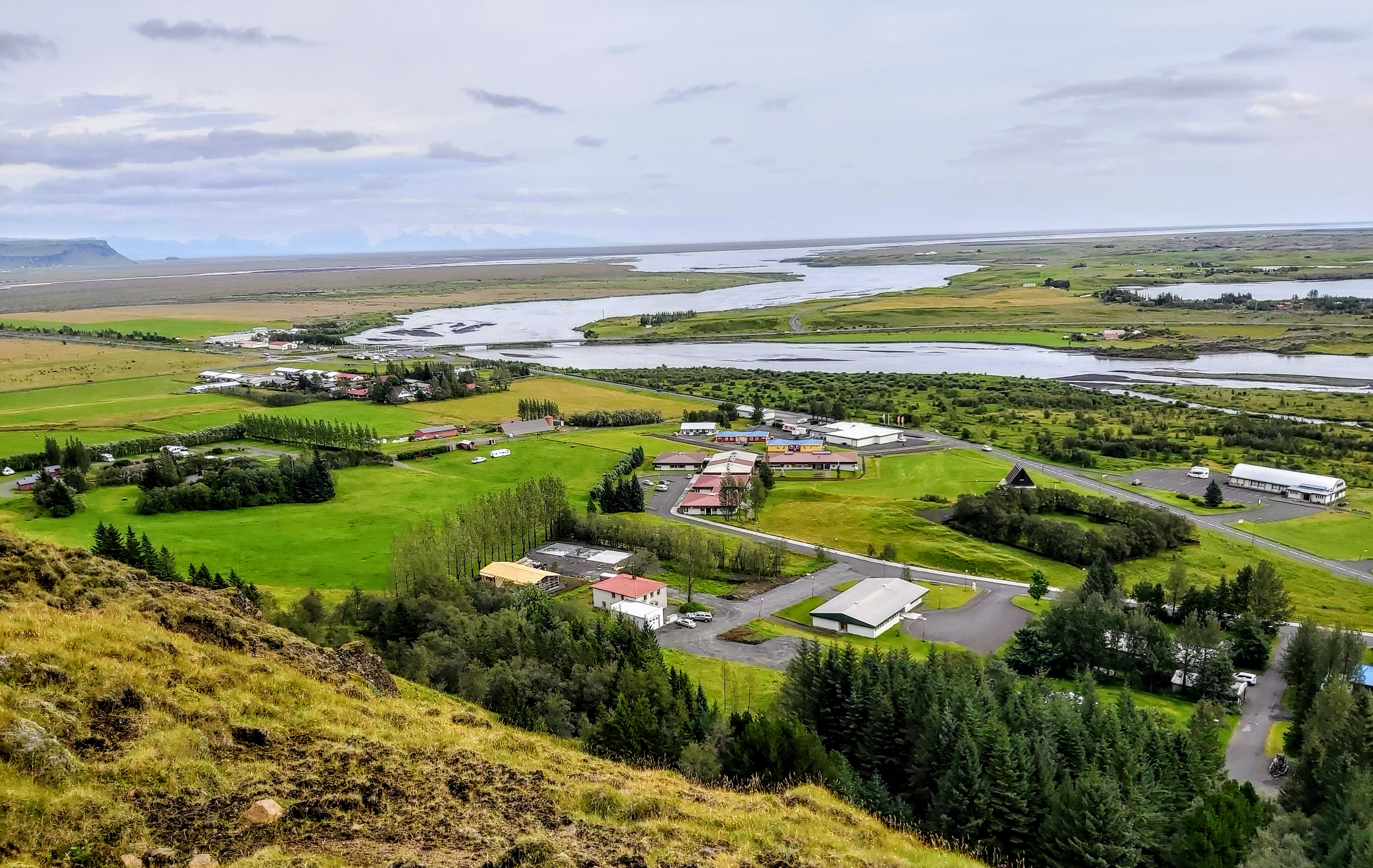 View from the ridge above Kirkjubæjarklaustur across the village, river flats, and the wider South Coast landscape.