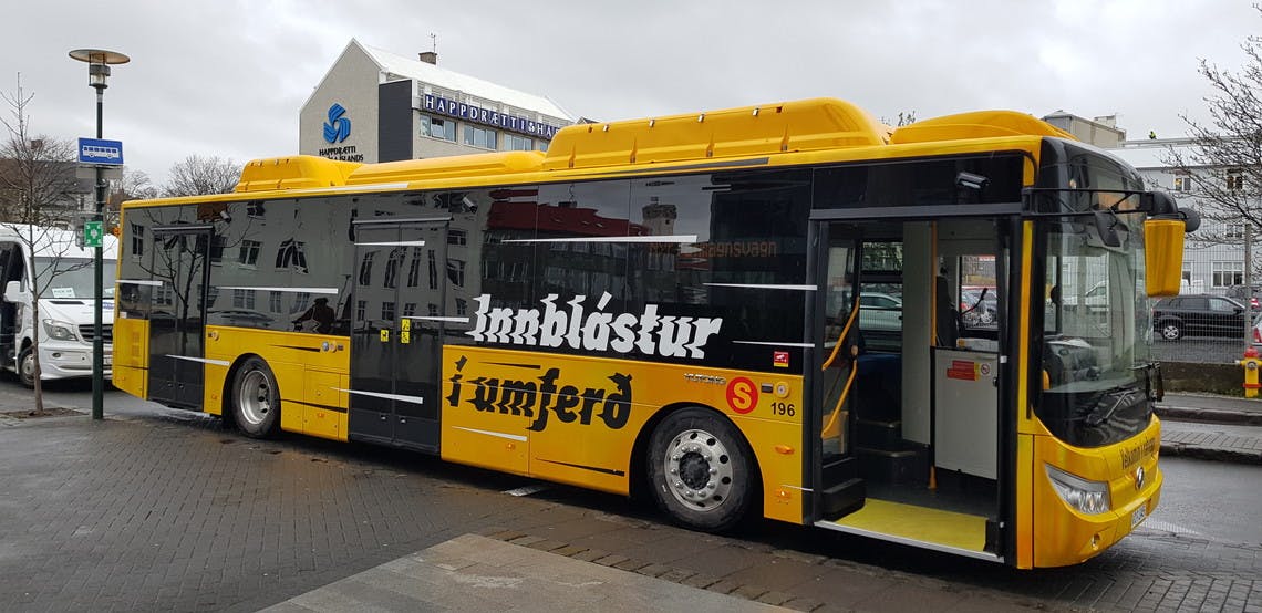 Yellow city bus stopped near Kringlan Shopping Mall.
