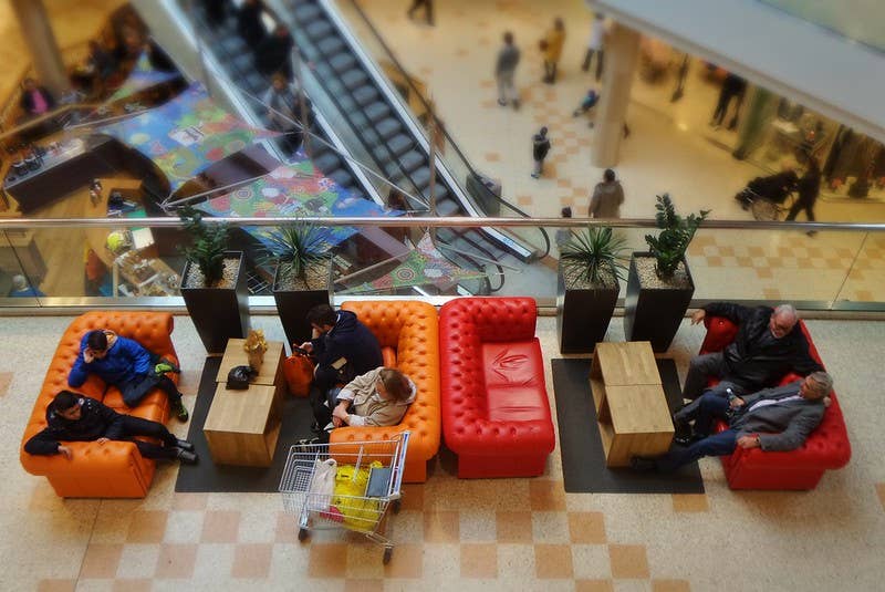 Seating area, escalators, and shoppers inside Kringlan.