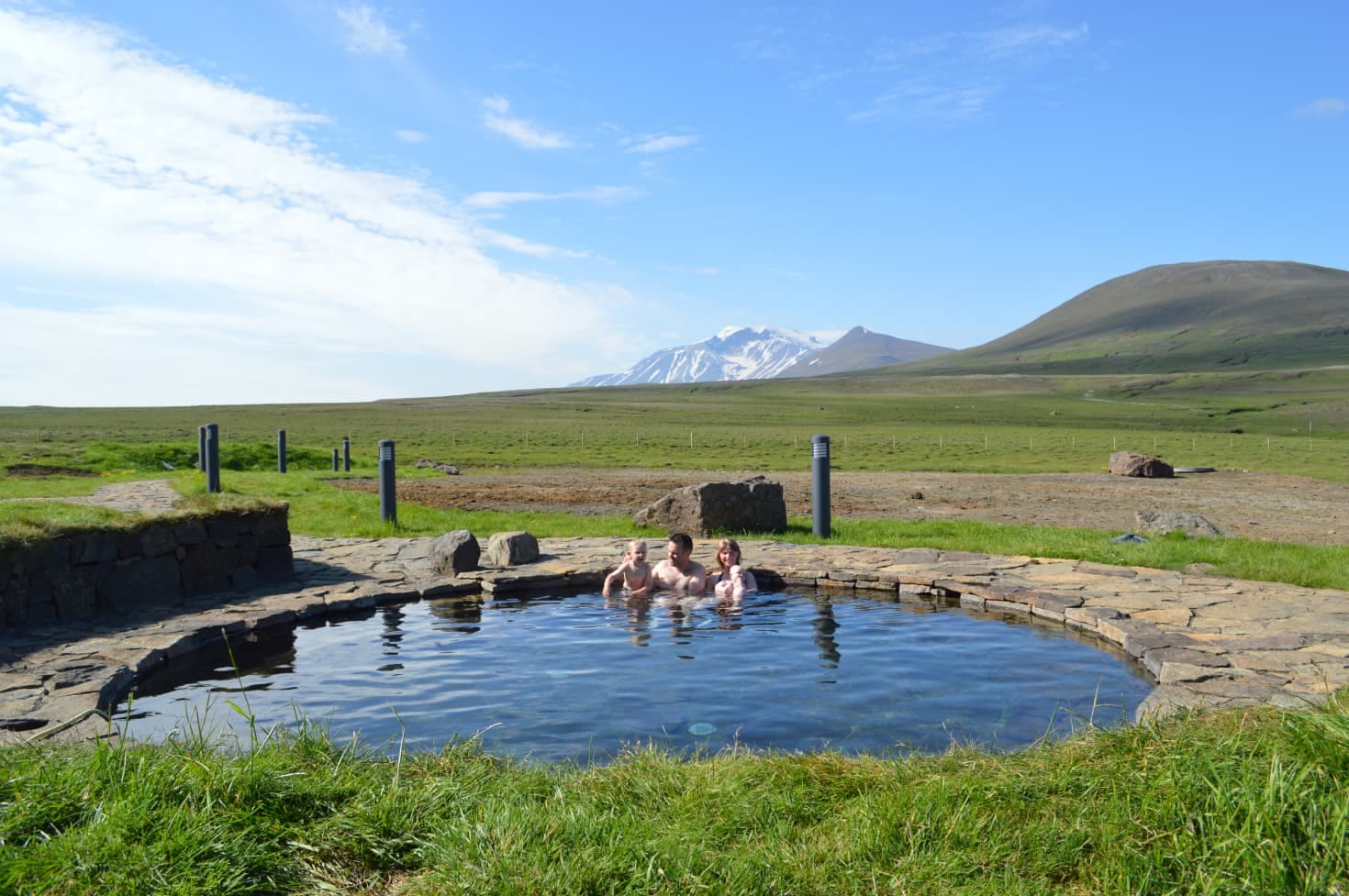 People soaking in the Laugarfell hot spring pool with East Iceland highland hills behind.