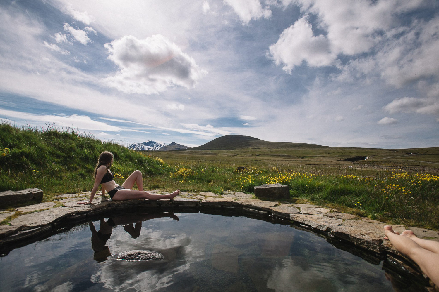 Visitor relaxing in a stone-built hot spring pool at Laugarfell in East Iceland.
