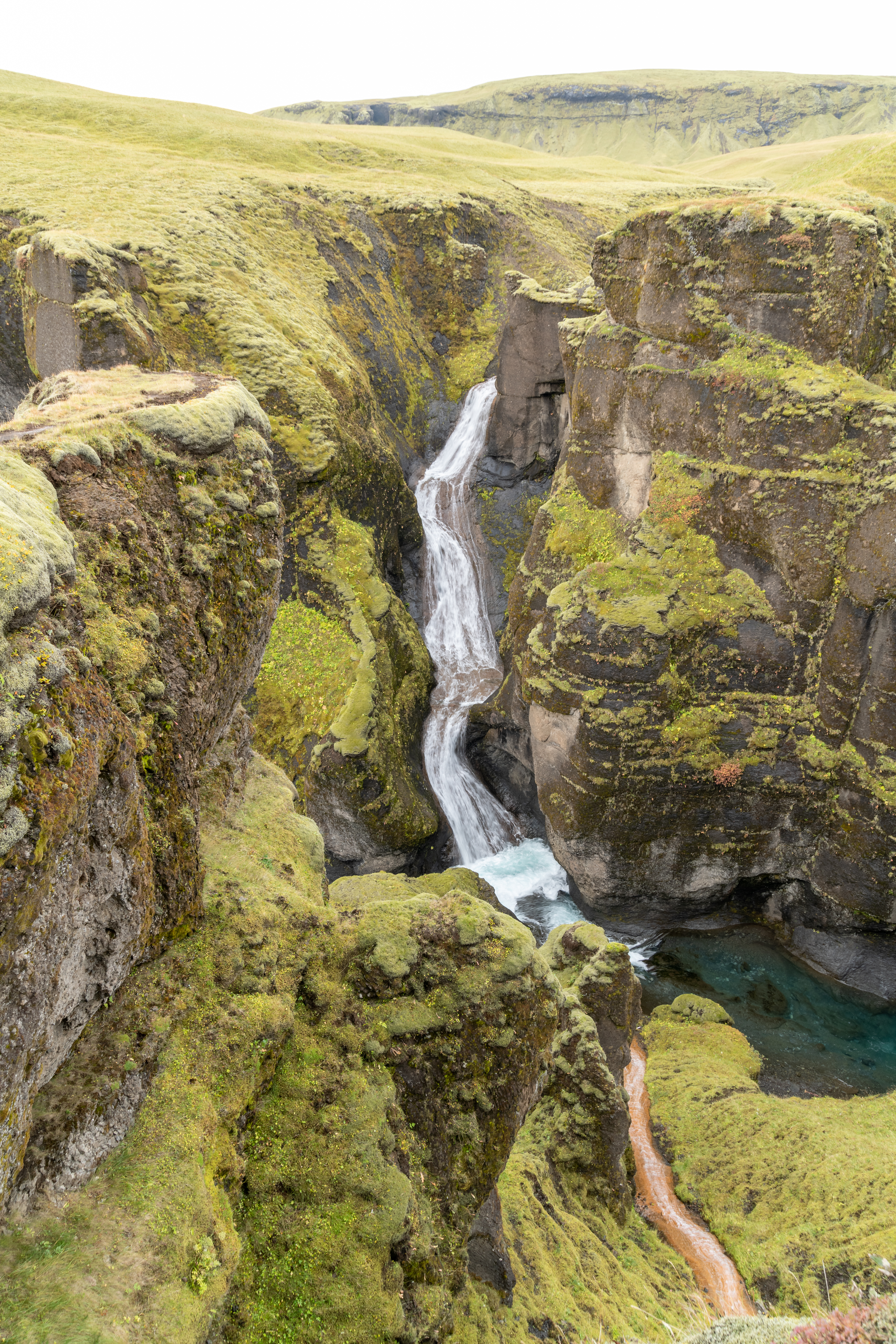 Mögáfoss waterfall framed by green canyon slopes in Fjaðrárgljúfur.