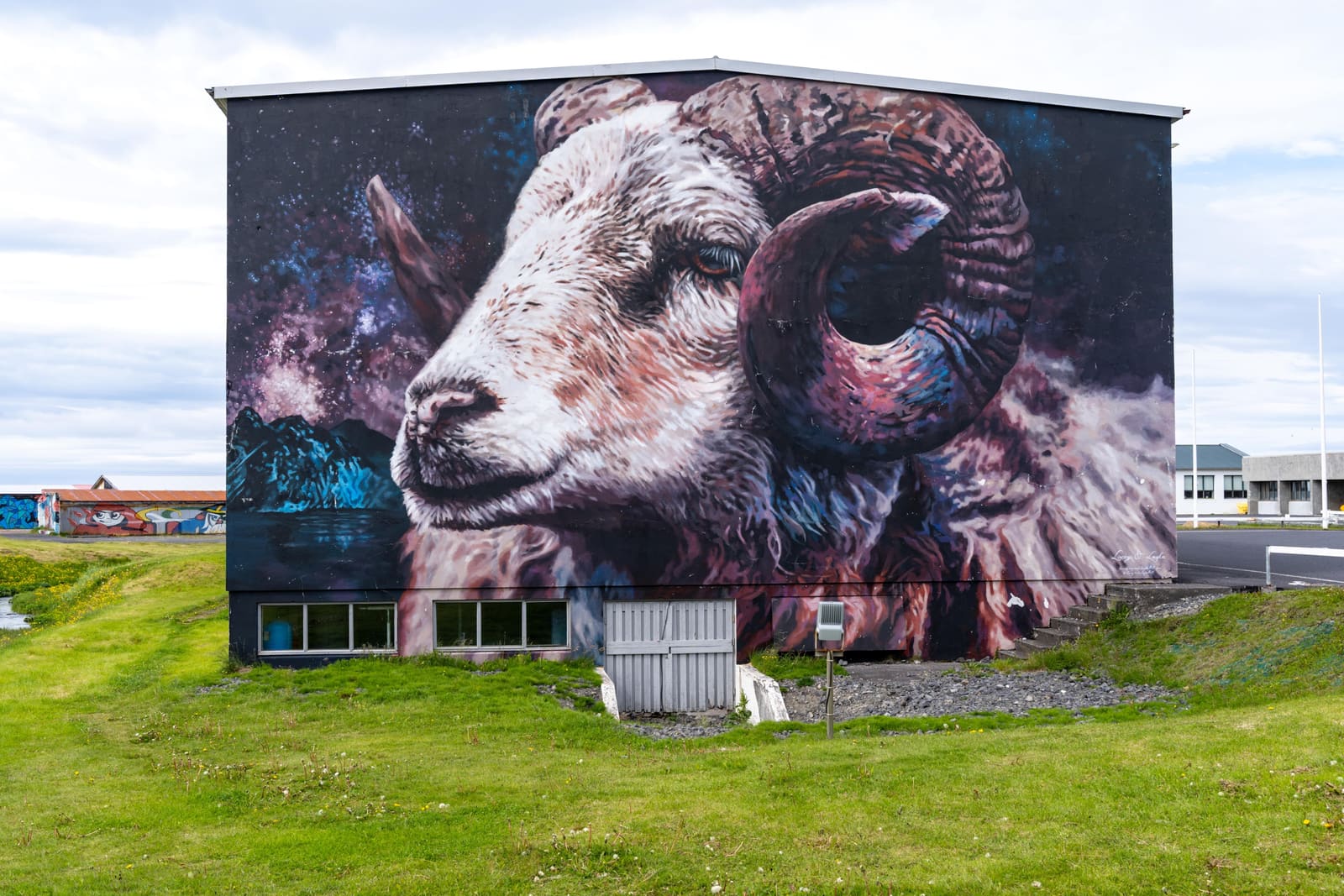 Large ram mural with a cosmic background painted on a building in Hellissandur.