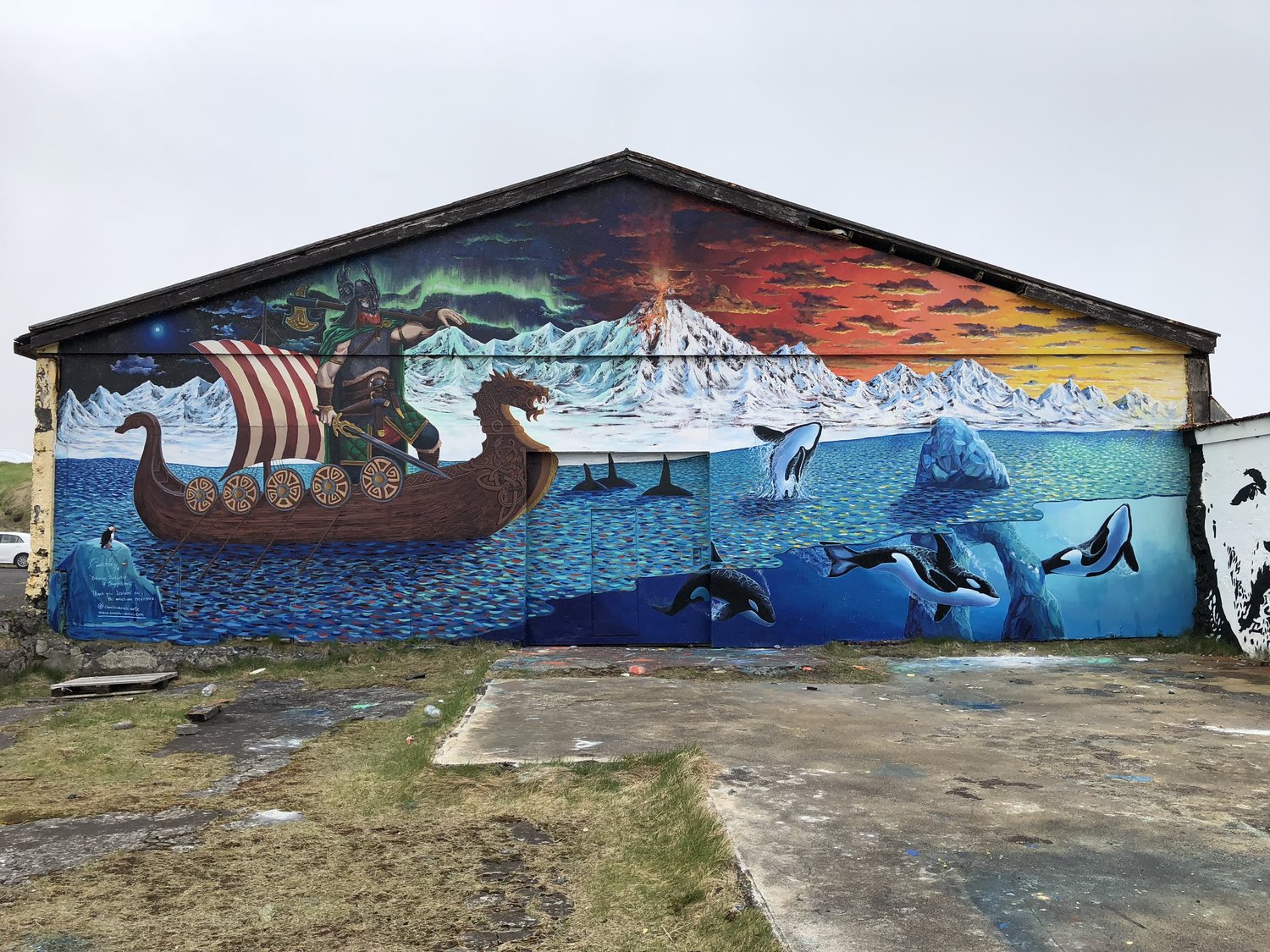 A Hellissandur mural showing a Viking ship, orcas, sea ice and mountains.