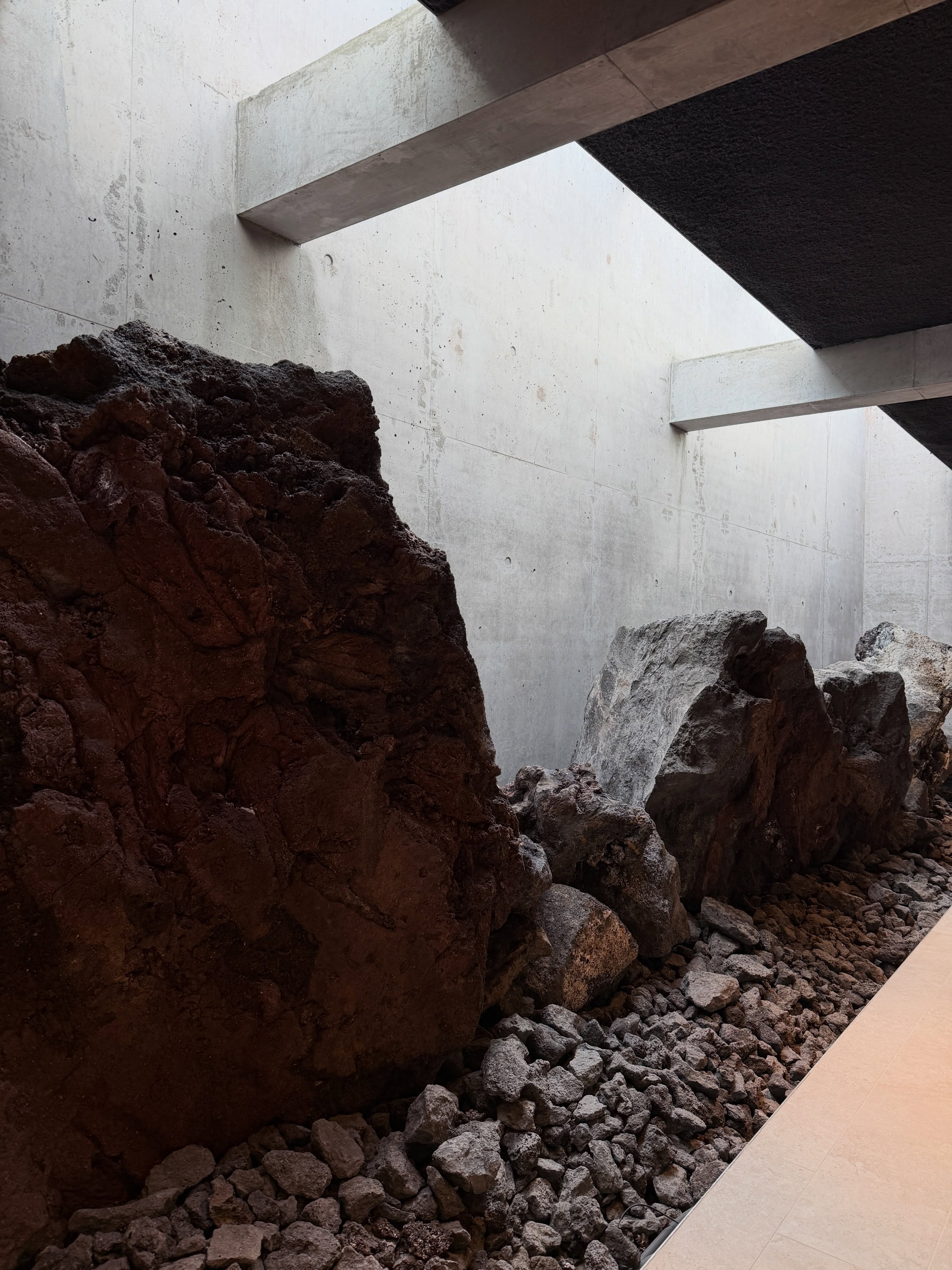 Red-brown lava formation rising through a light well in the new Earth Lagoon Mývatn steam area.