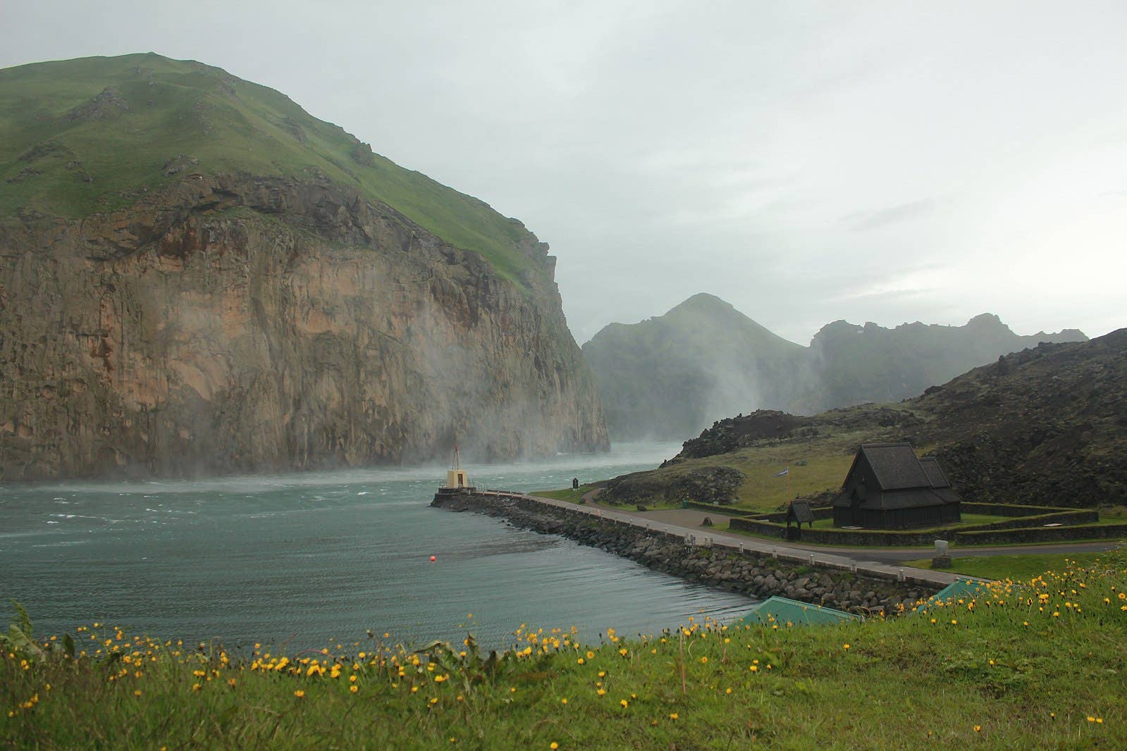 Skansinn Fort area beside Heimaey harbor with historic stonework and island backdrop.