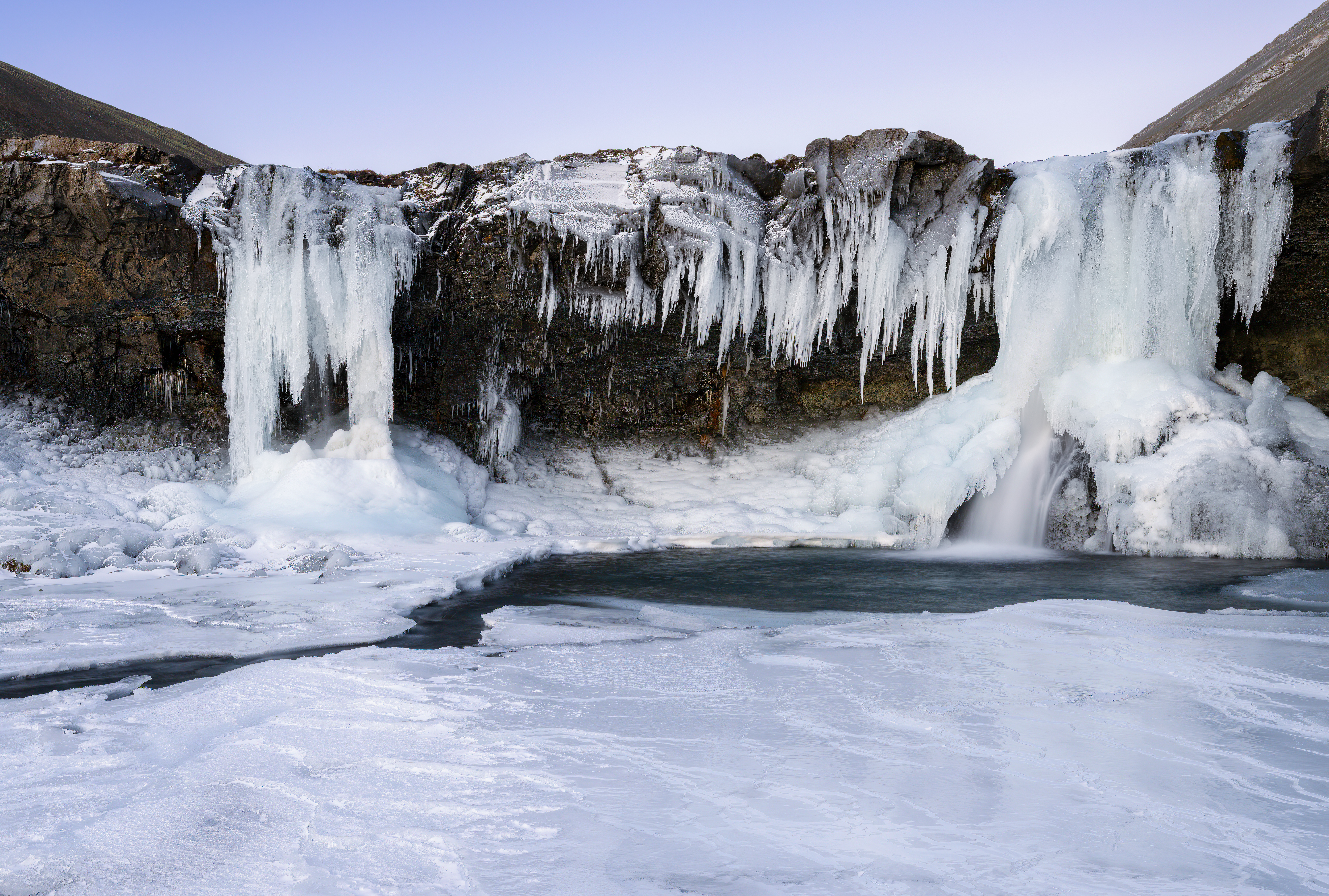 Frozen Skútafoss waterfall and smaller nearby falls in East Iceland.