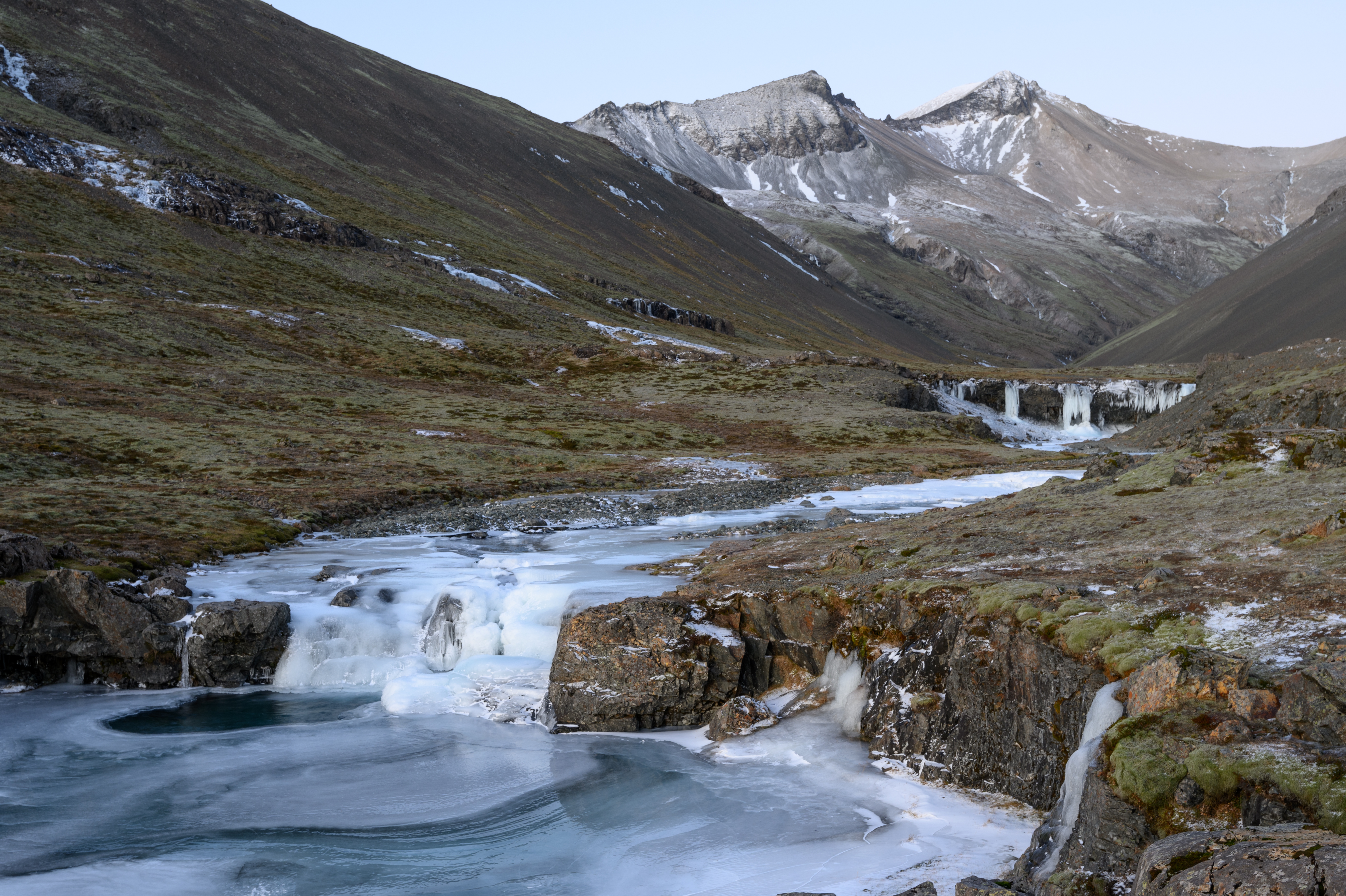 Frozen Skútafoss falls with mountain peaks in the Hornafjörður area.