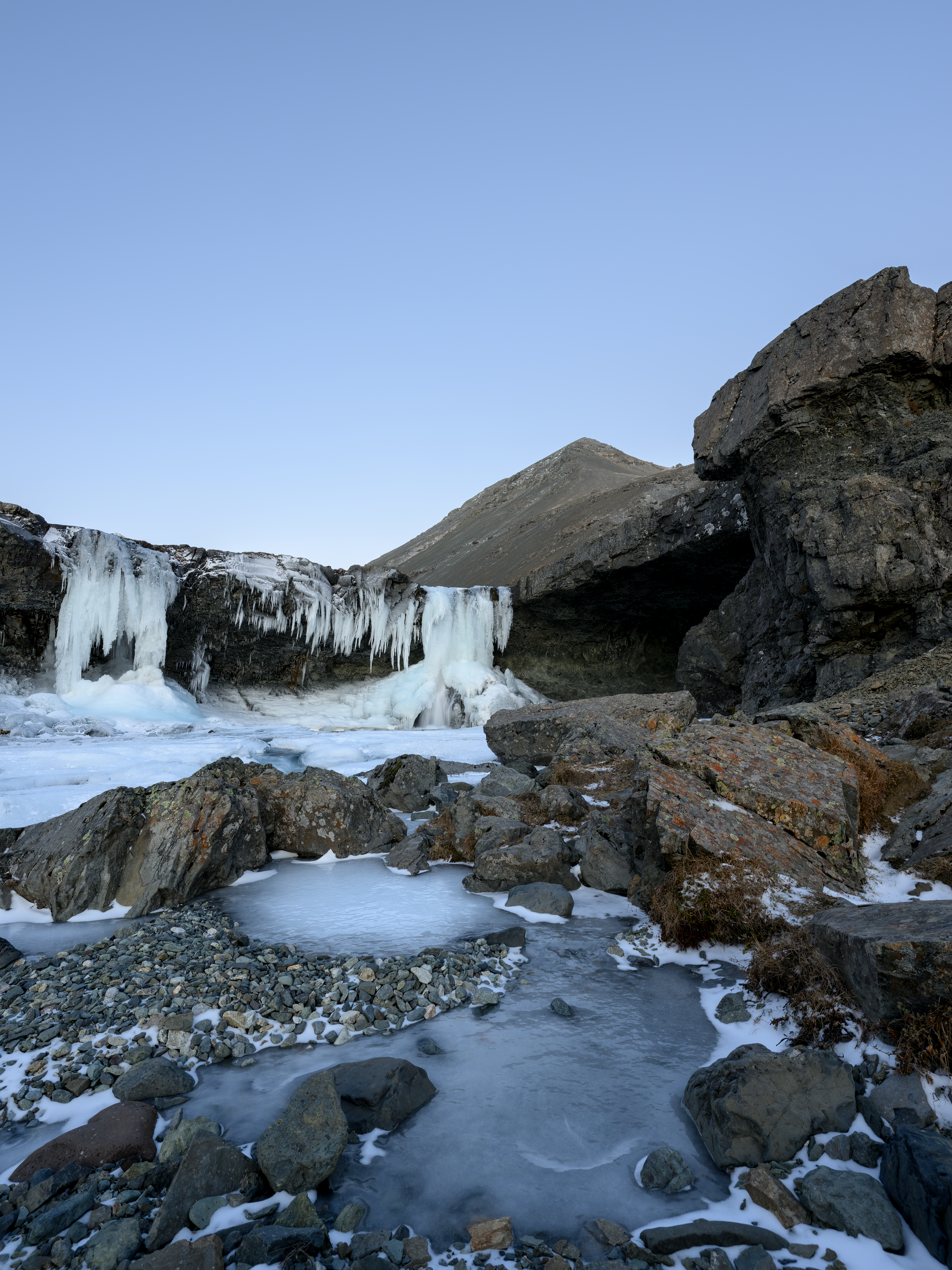 Frozen Skútafoss waterfall framed by an overhanging cave wall.
