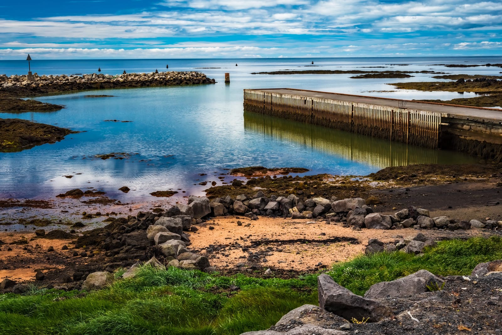 Rocky Stokkseyri shore and small harbor water below a wide South Iceland sky