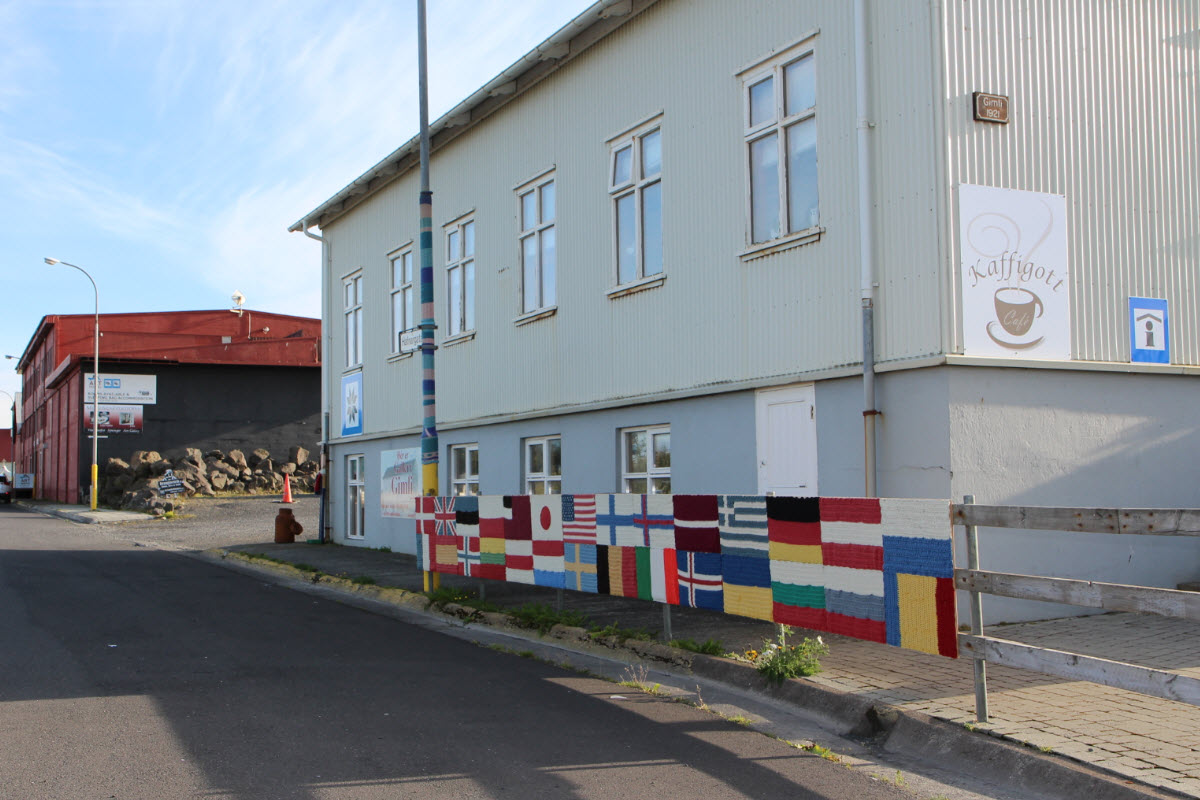 Street beside Stokkseyri cultural buildings with painted flag panels on a low wall