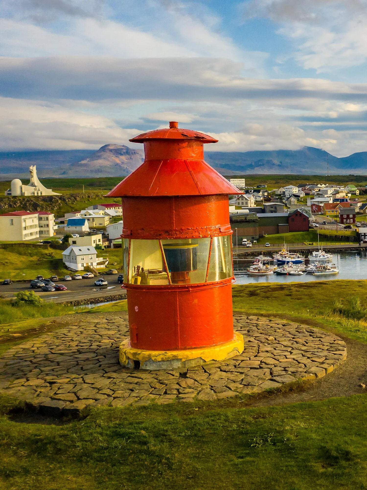 Red Súgandisey lighthouse above Stykkishólmur town, harbor boats, and Stykkishólmskirkja church.