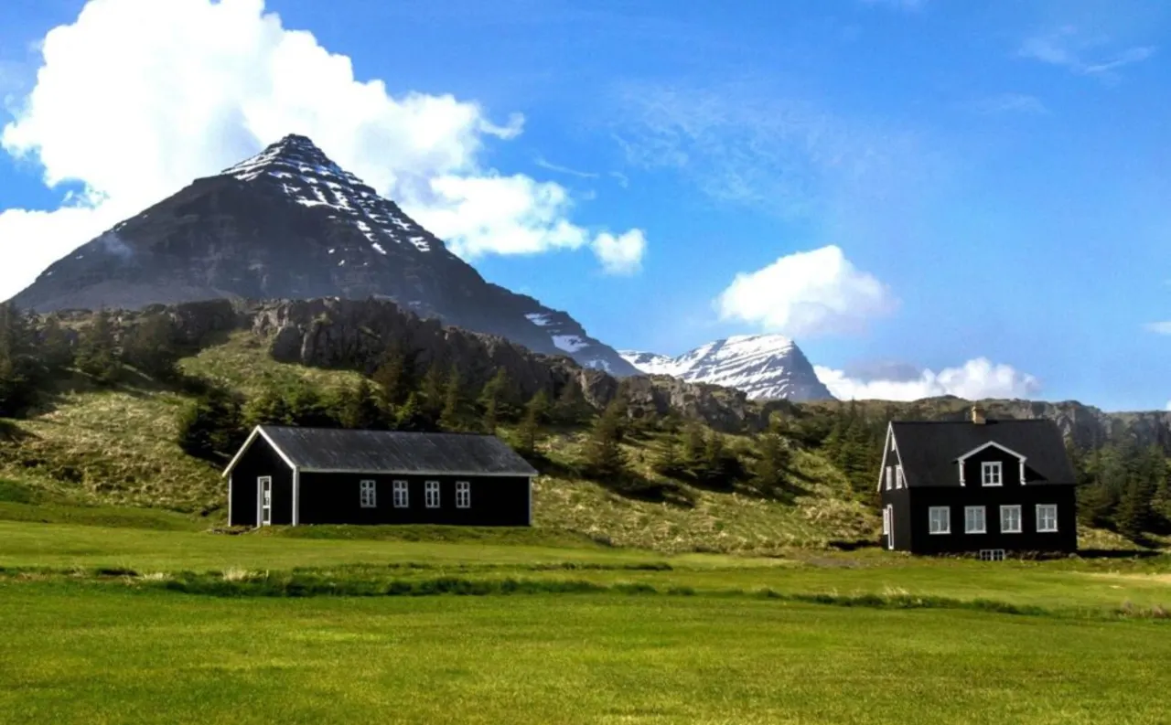 Teigarhorn farm buildings and green fields below Búlandstindur