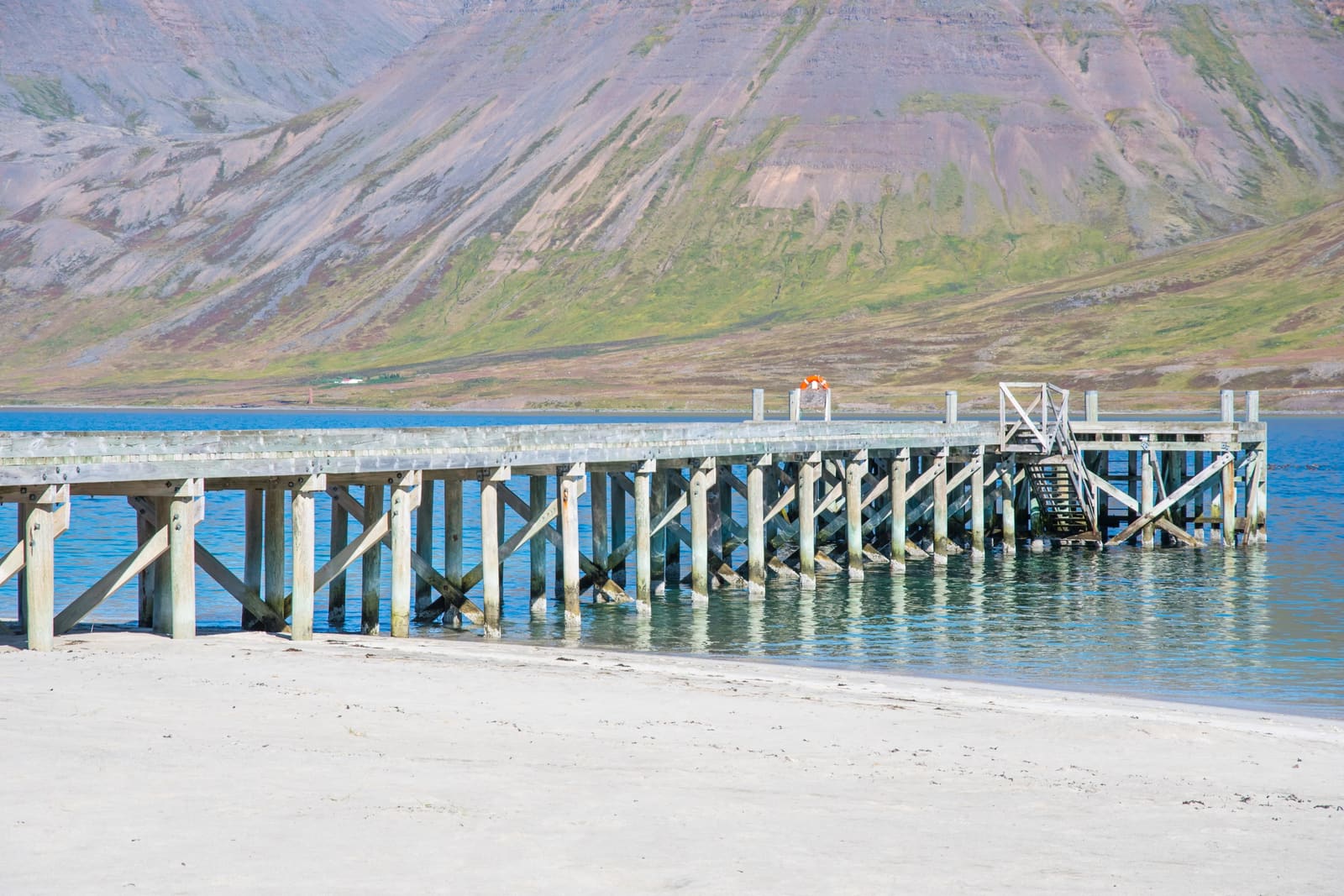Side view of Önundarfjörður Pier with its wooden supports standing above Holtsfjara beach.