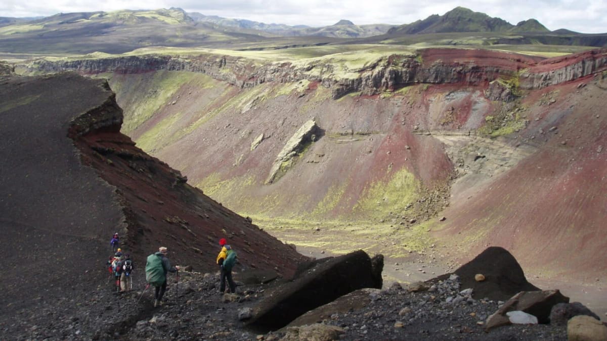 Hikers crossing colorful volcanic terrain near Eldgjá in the Uxatindar highland area.