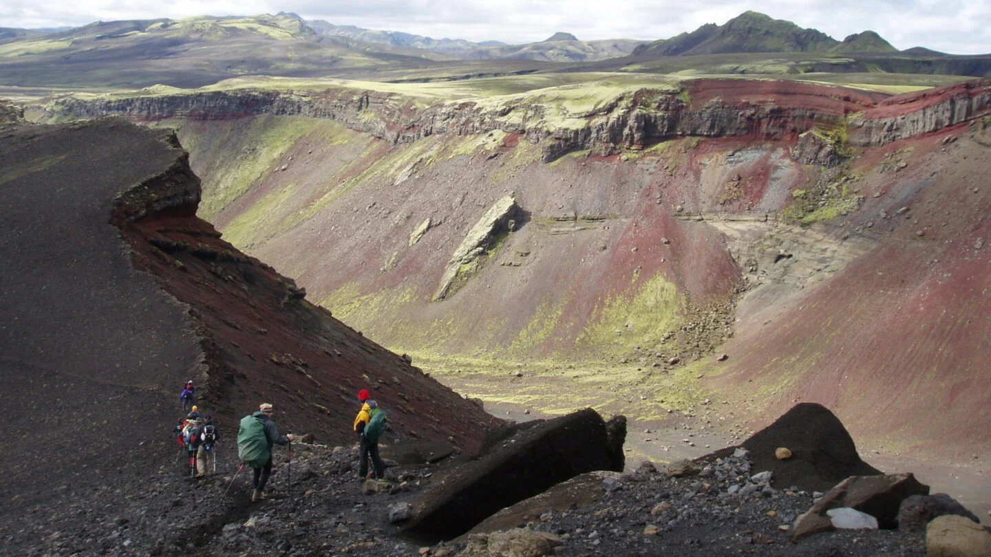 Hikers crossing colorful volcanic terrain near Eldgjá in the Uxatindar highland area.