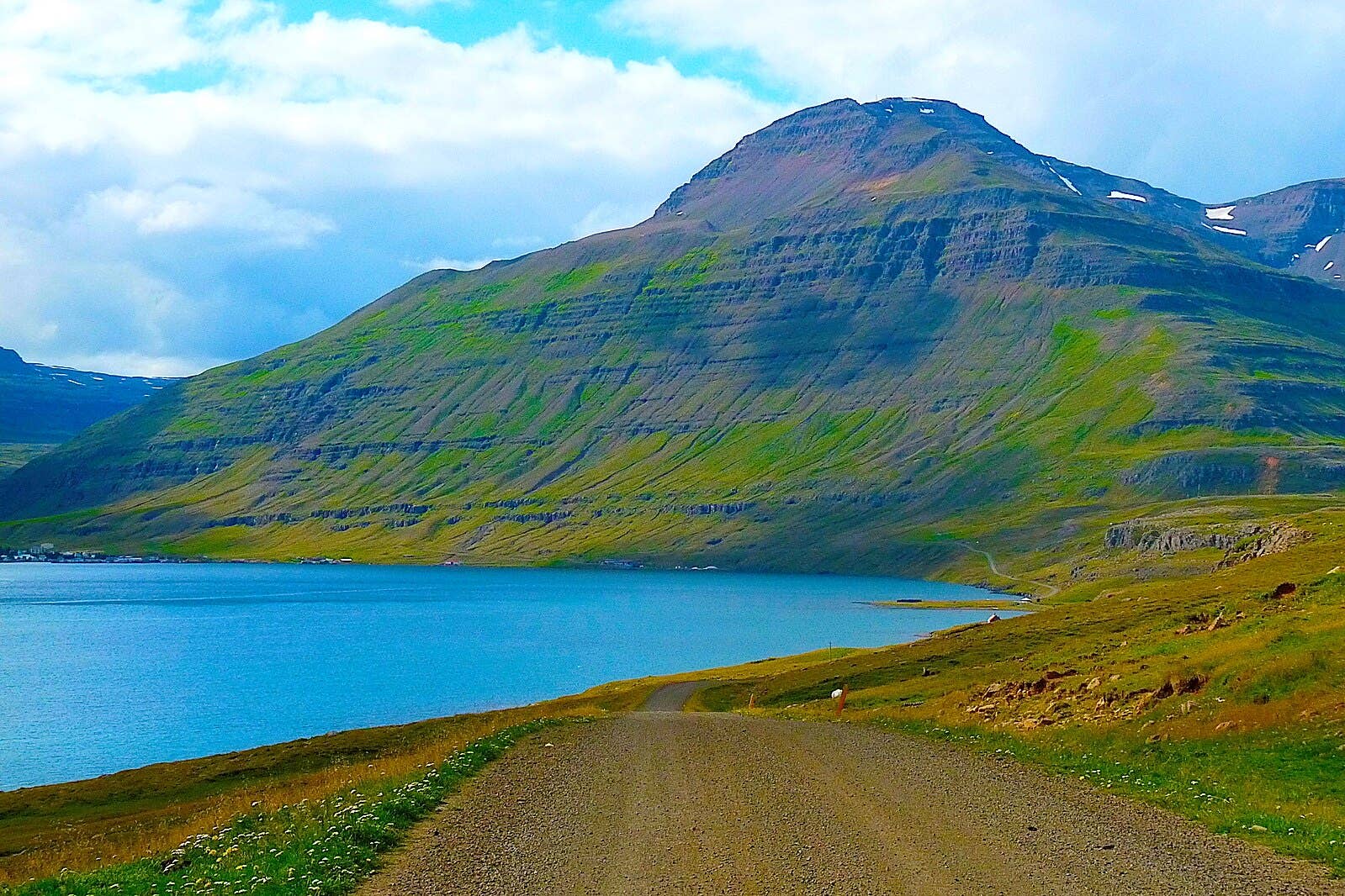 Gravel road and fjord view near the Vestdalsfossar trail approach outside Seyðisfjörður.