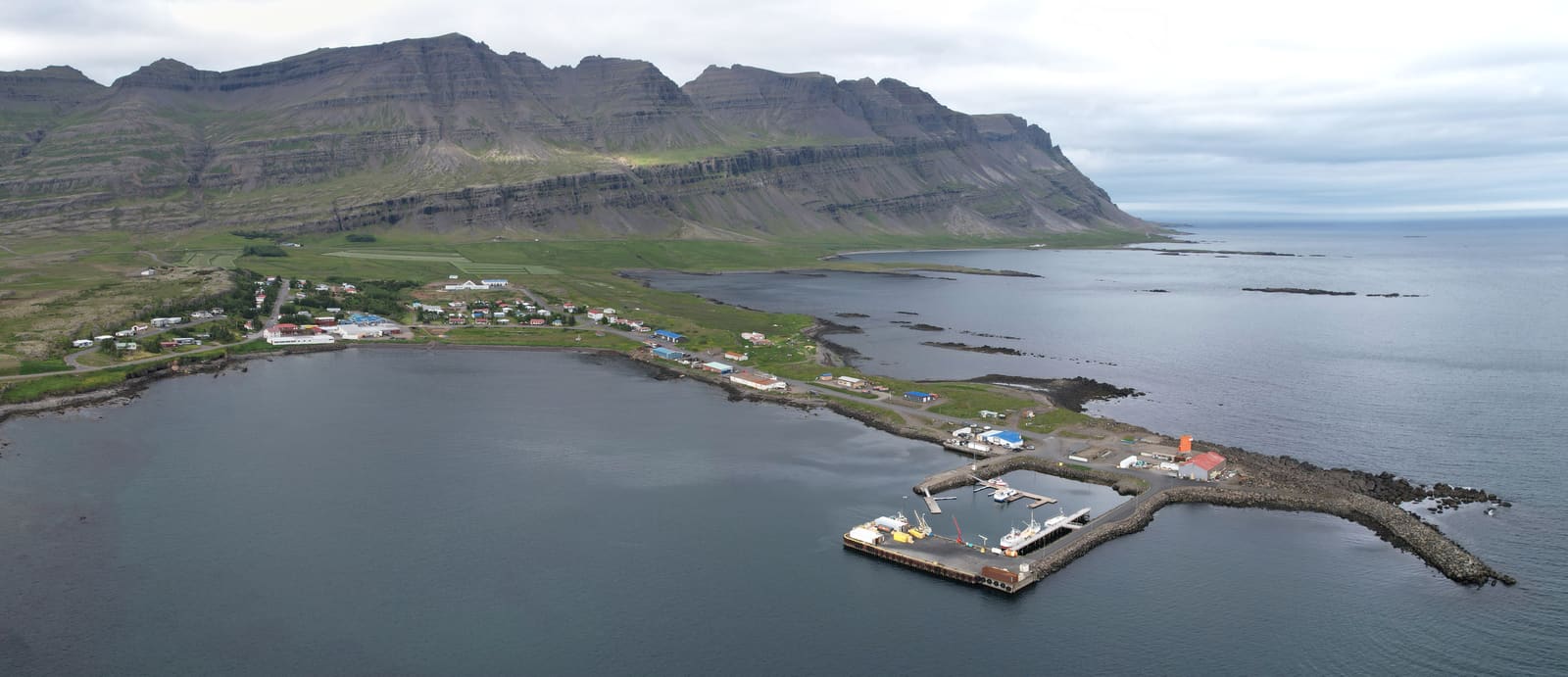 Small Eastfjords village beside a sheltered harbor and steep mountains