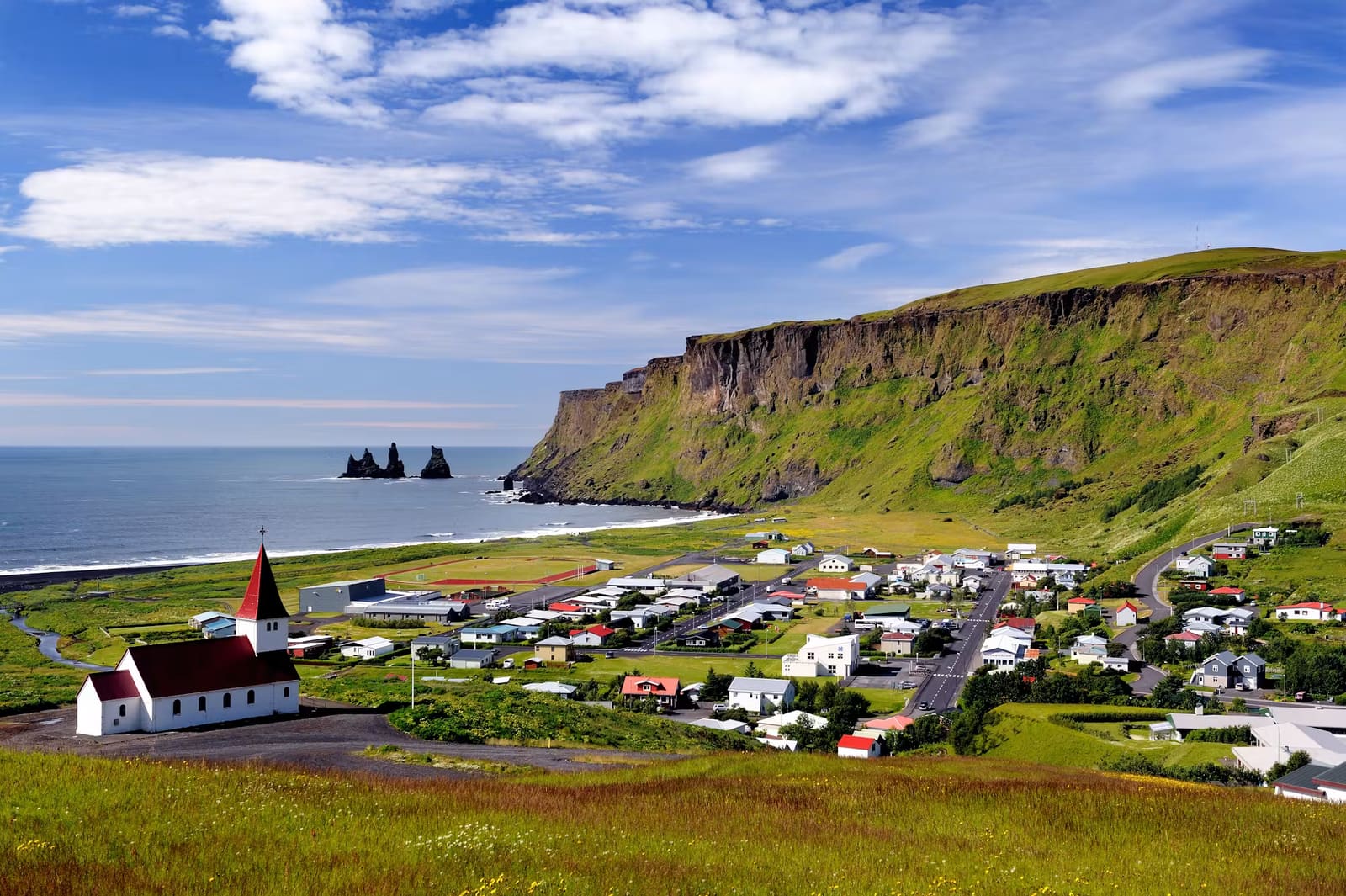 Vík village, hilltop church, and black-sand coast seen from above town