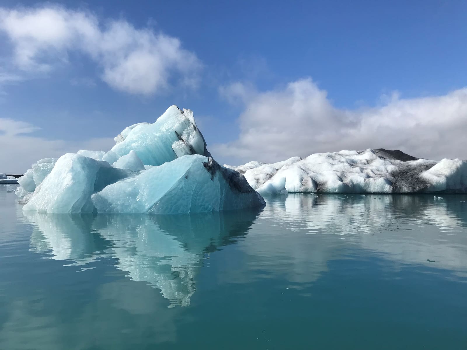 Blue-white icebergs floating across calm water at Jökulsárlón glacier lagoon