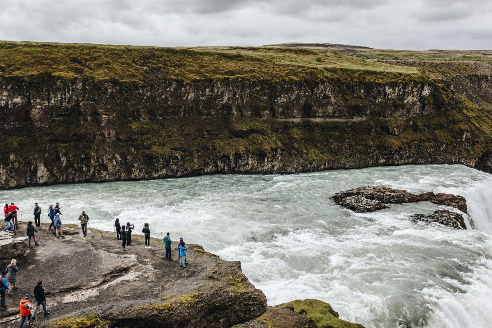 Visitors beside the fast river and canyon at Gullfoss