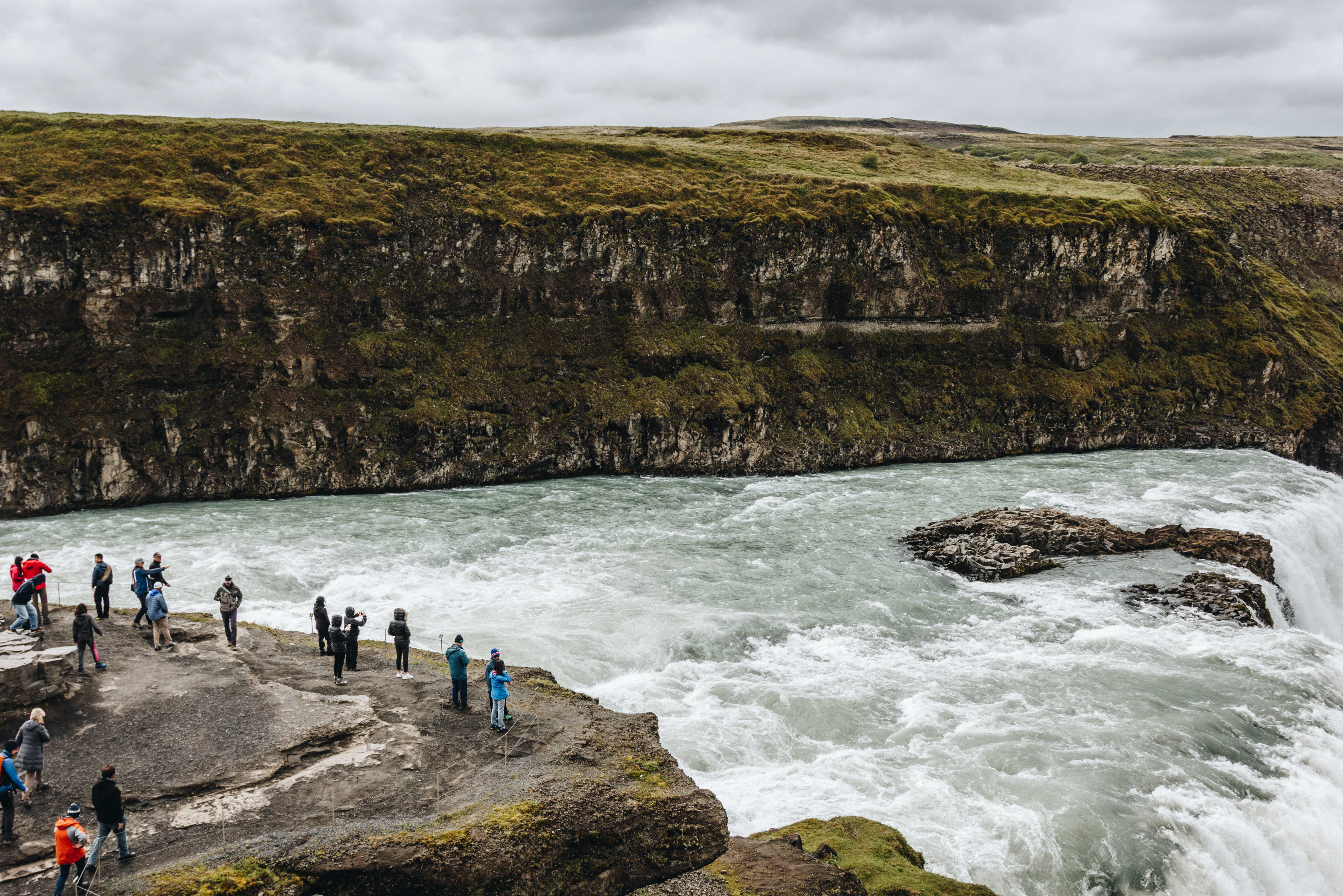 Visitors beside the fast river and canyon at Gullfoss