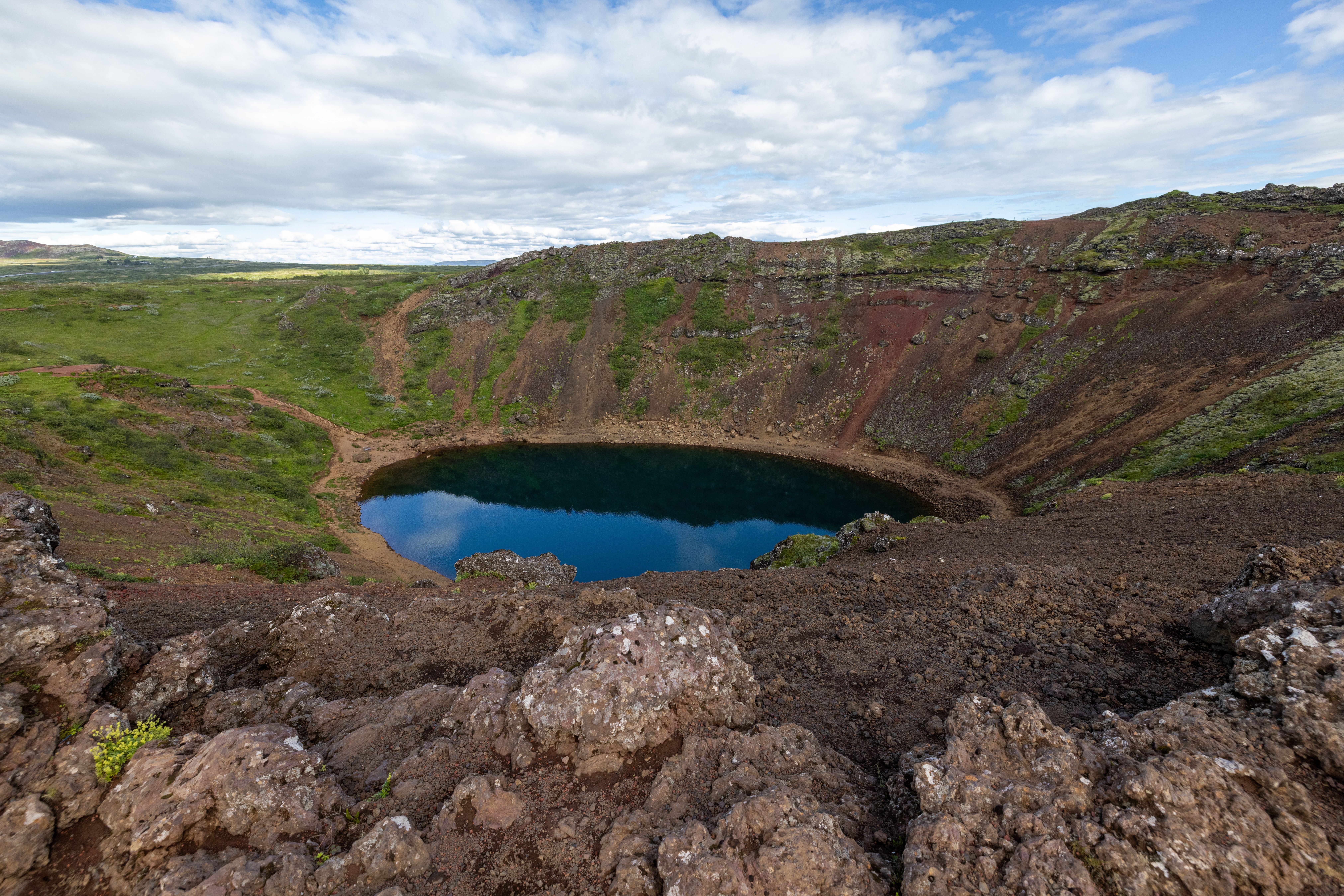 Blue lake inside Kerið's red volcanic crater