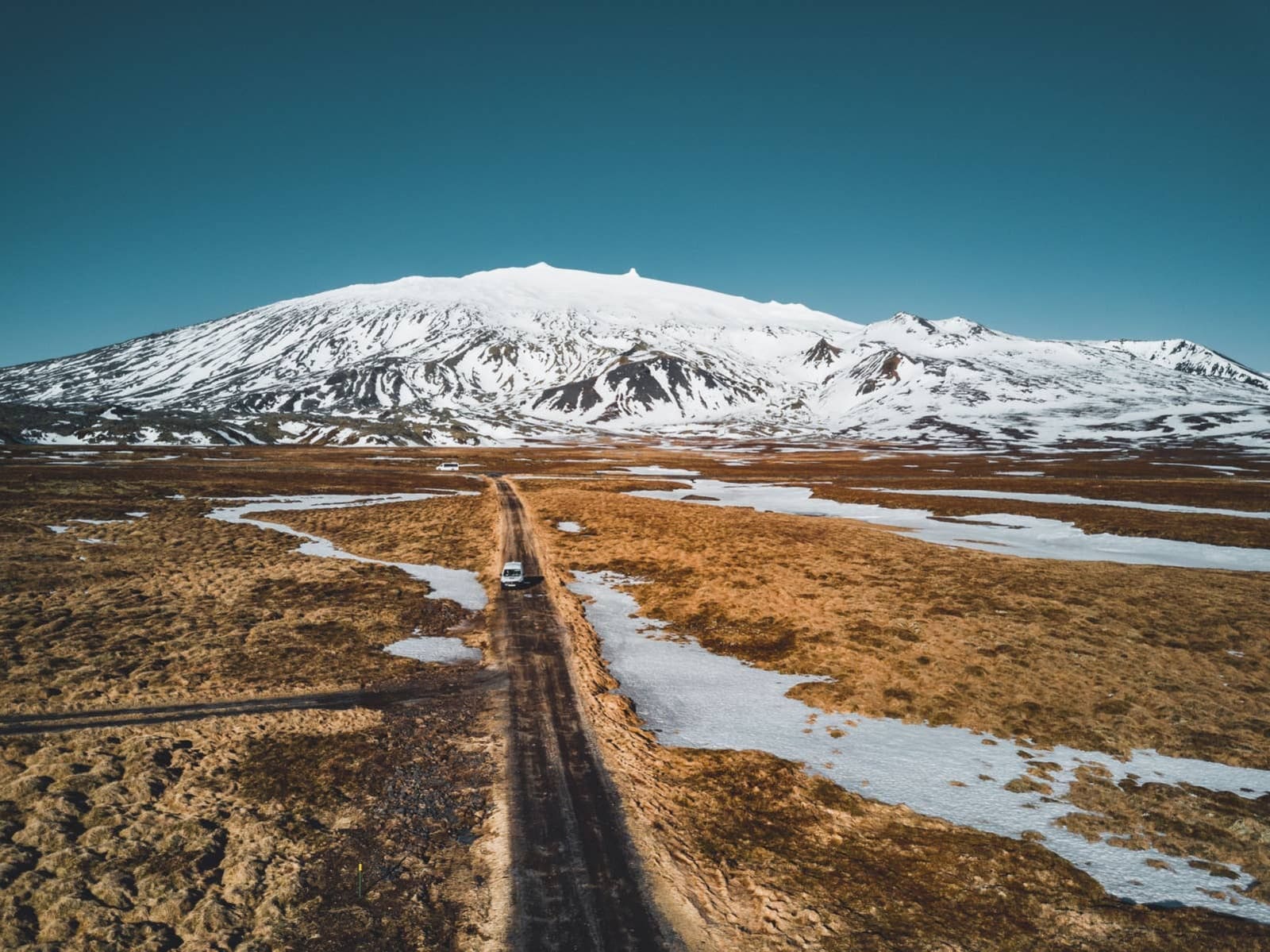 A road crosses snowy ground below Snæfellsjökull on the Snæfellsnes Peninsula.