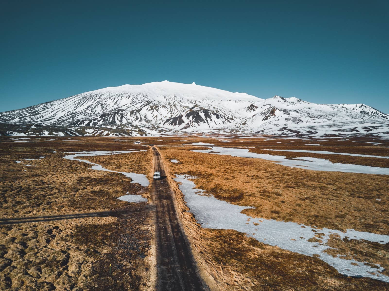 A road crosses snowy ground below Snæfellsjökull on the Snæfellsnes Peninsula.