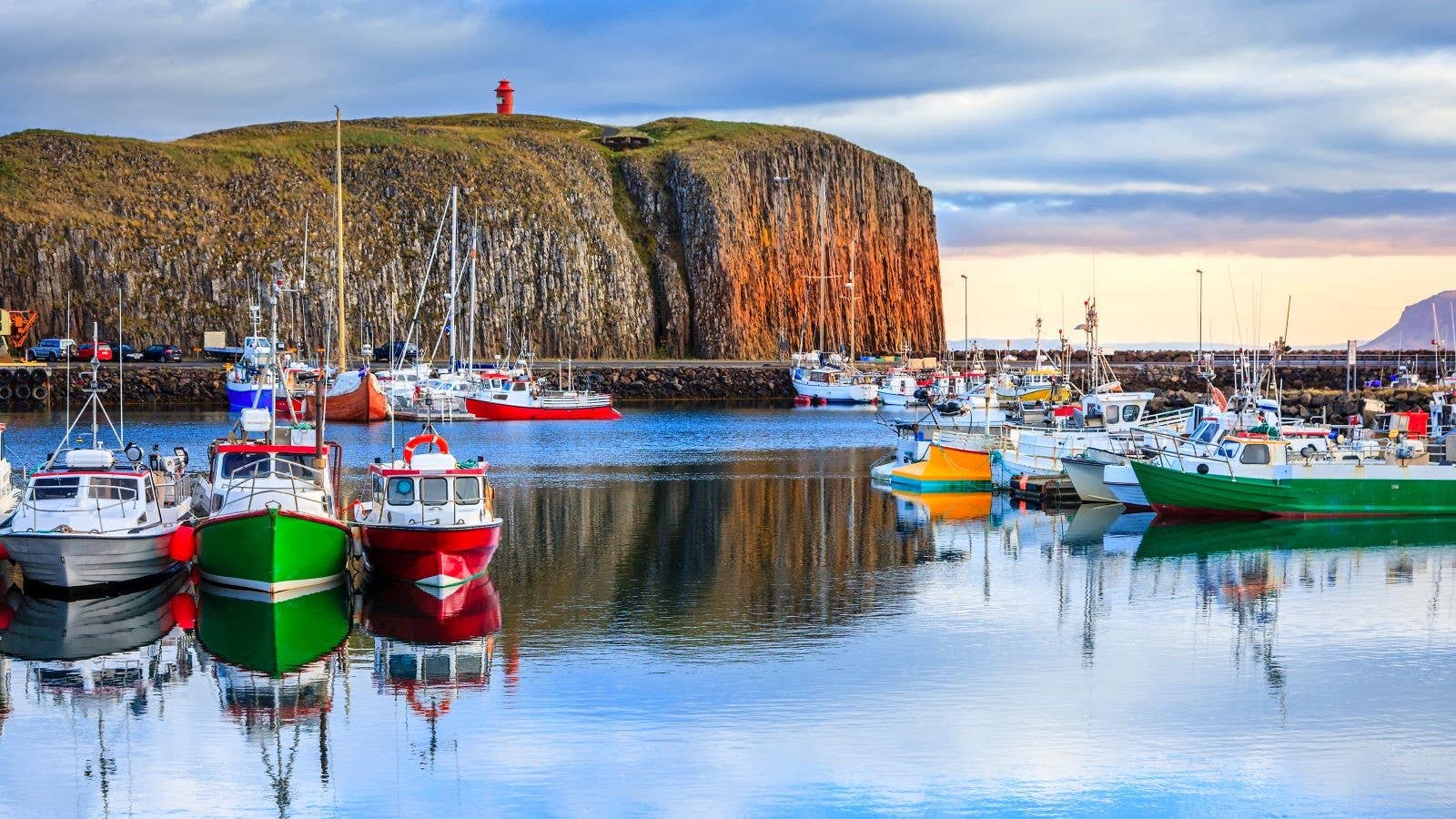 Boats in Stykkishólmur harbor beneath the basalt island viewpoint on Snæfellsnes.