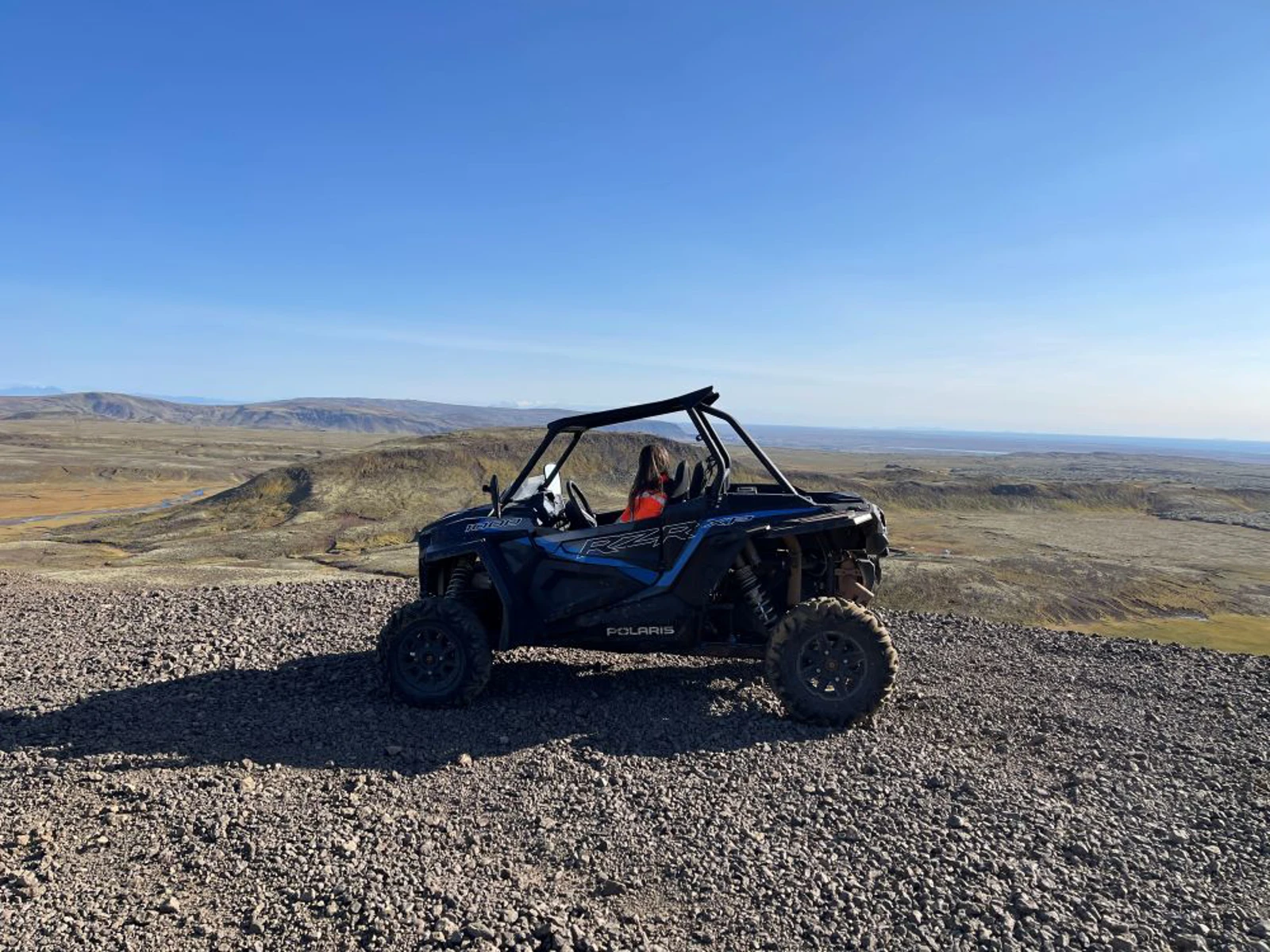 A side-by-side buggy parked on a high gravel track above open Icelandic hills.