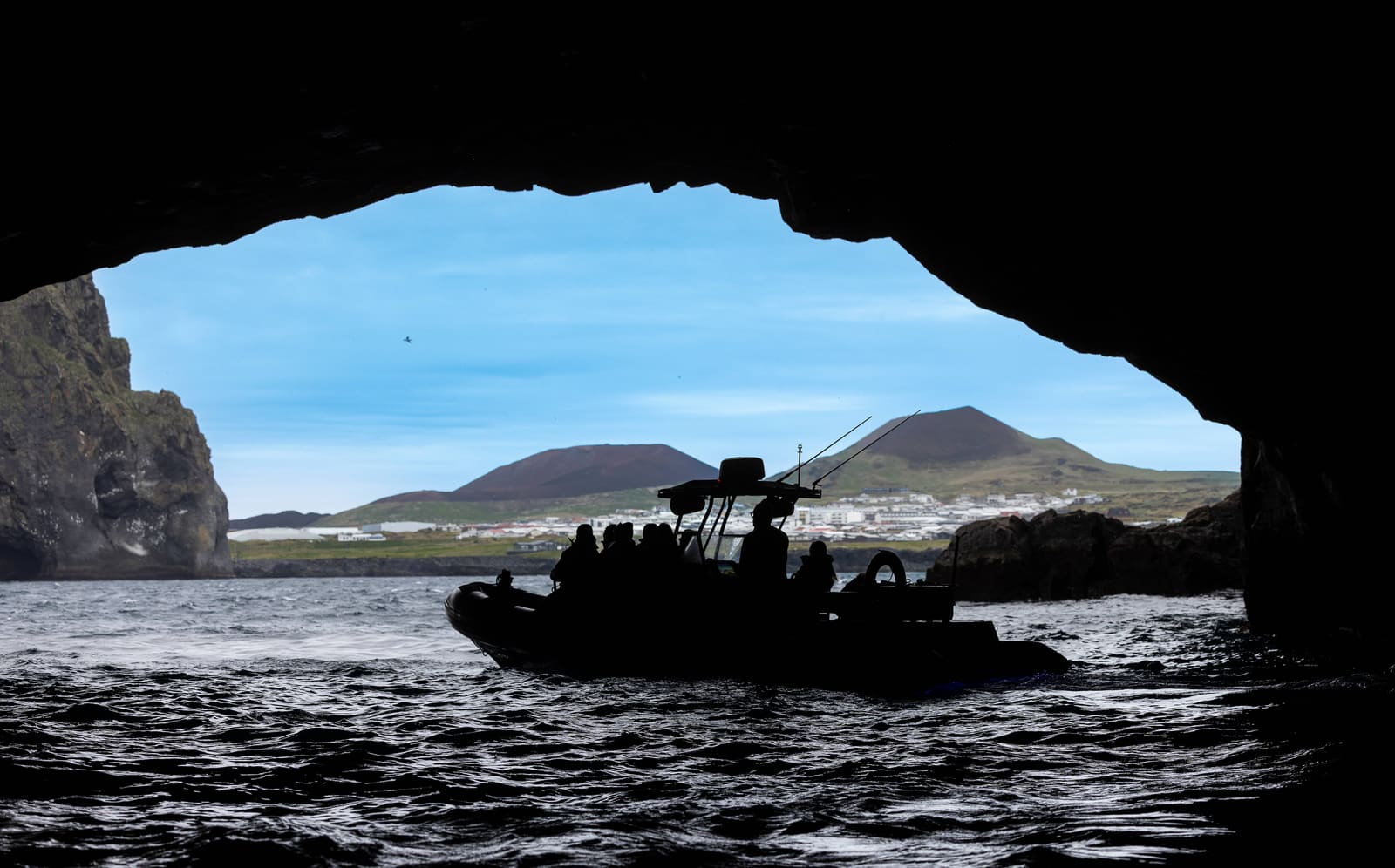 Passenger RIB silhouetted inside a sea cave off Heimaey in the Westman Islands