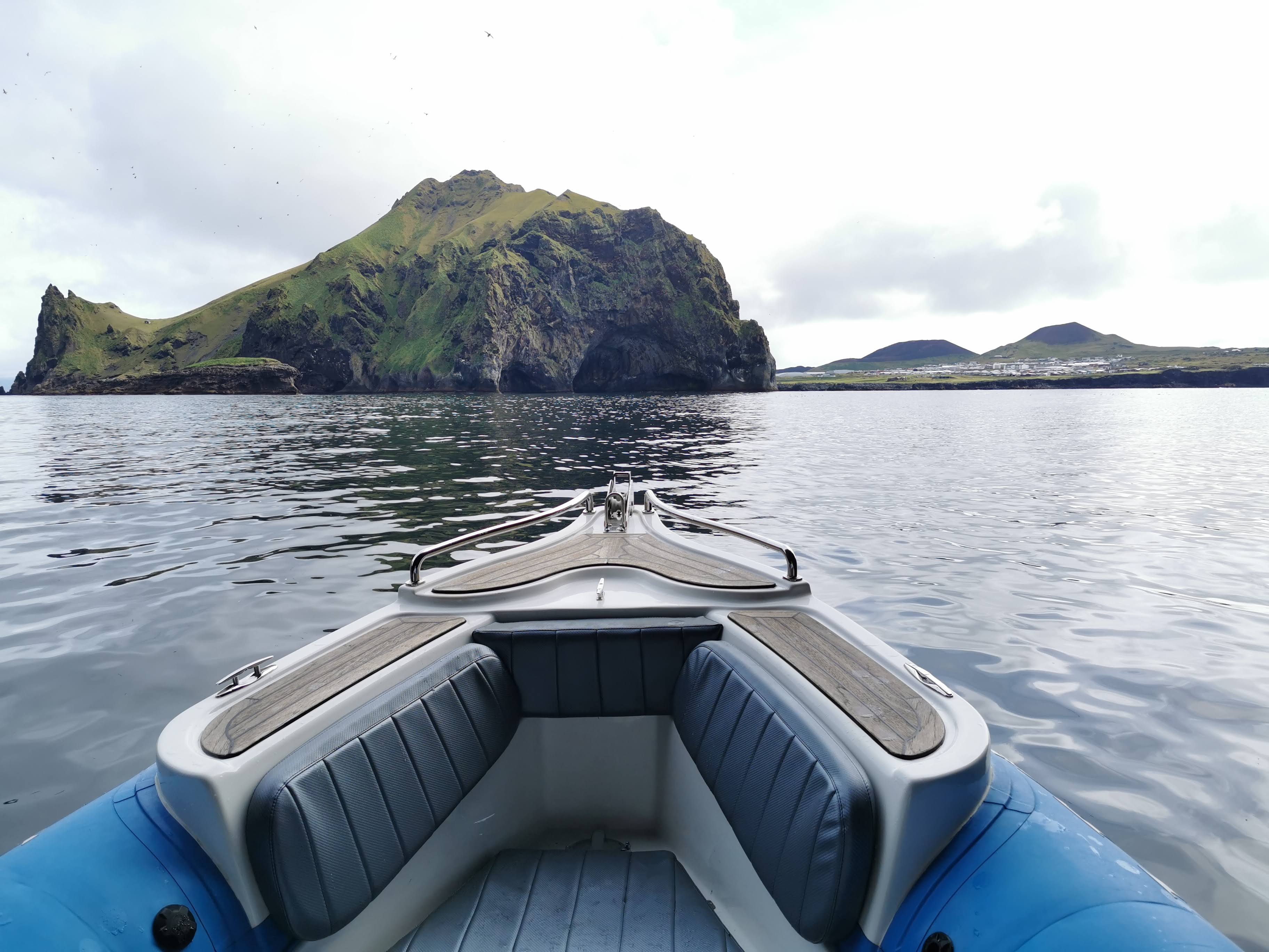 Bow of a passenger boat facing Heimaey cliffs and coastal caves
