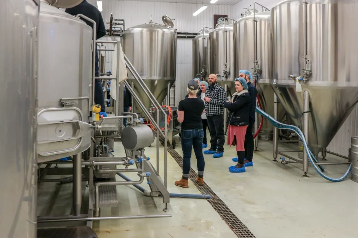 Visitors listening to a guide among stainless tanks on an Icelandic brewery floor