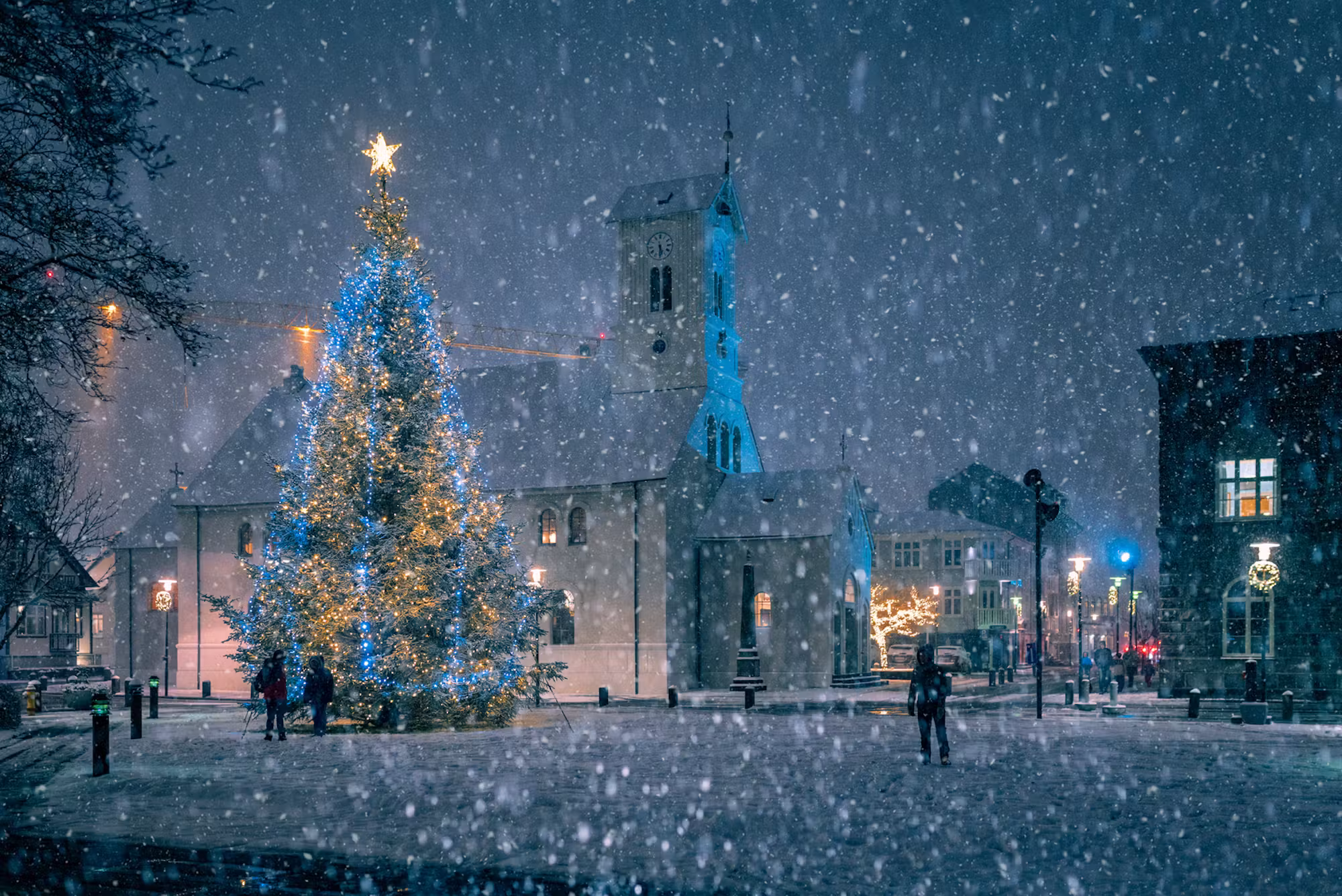 Lit Christmas tree and Dómkirkjan across snow-covered Austurvöllur in Reykjavík