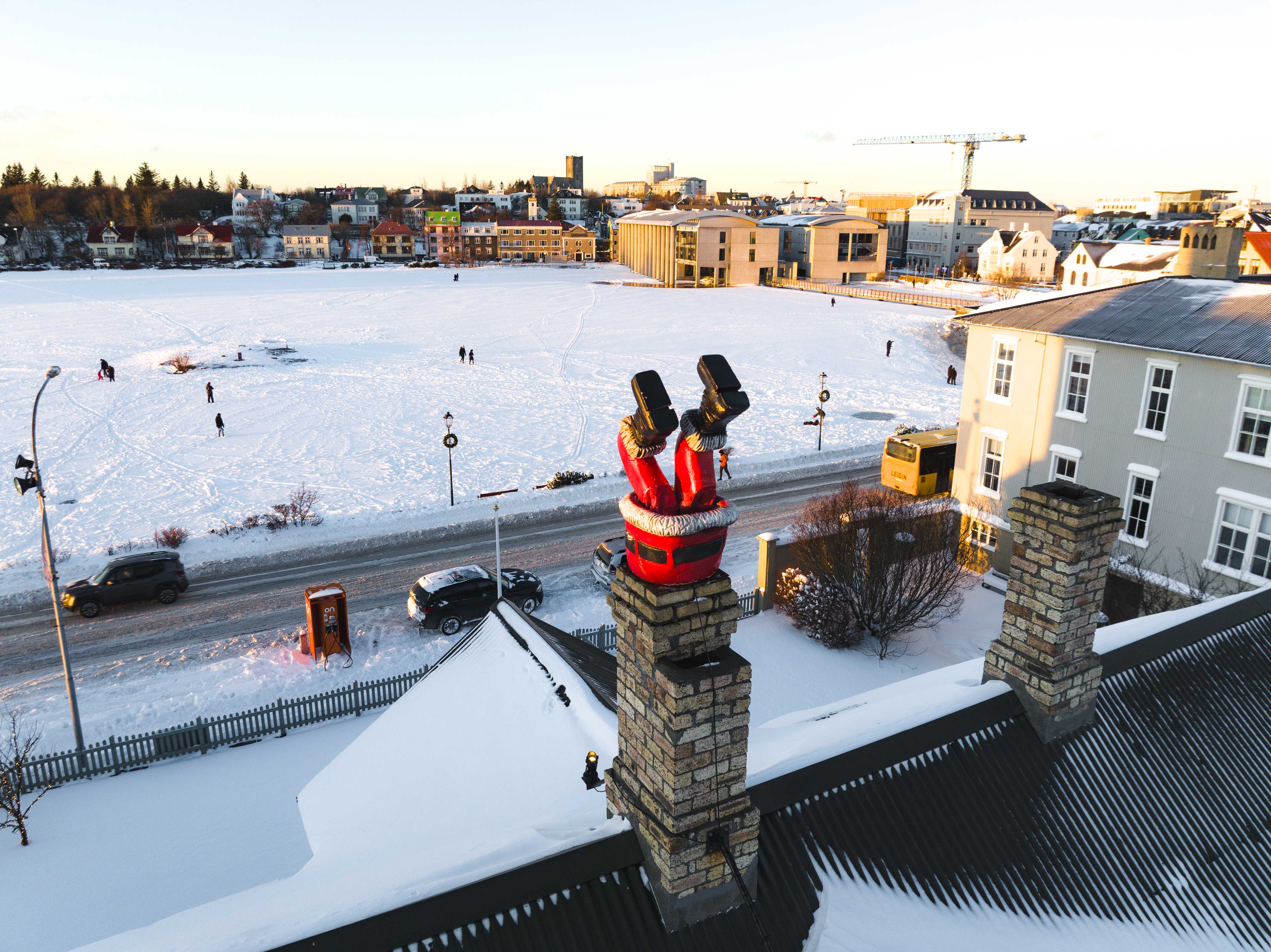 Snow-covered Tjörnin and central Reykjavík with a red Santa figure on a chimney