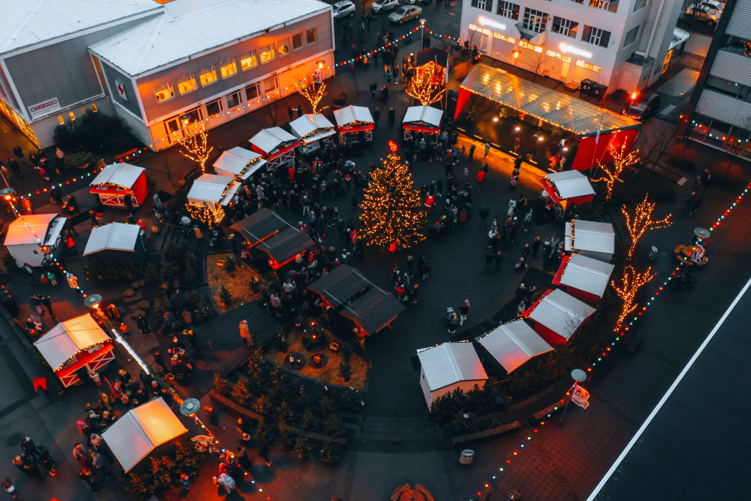 Overhead view of an Icelandic Christmas market with huts, visitors, lights, and a decorated tree