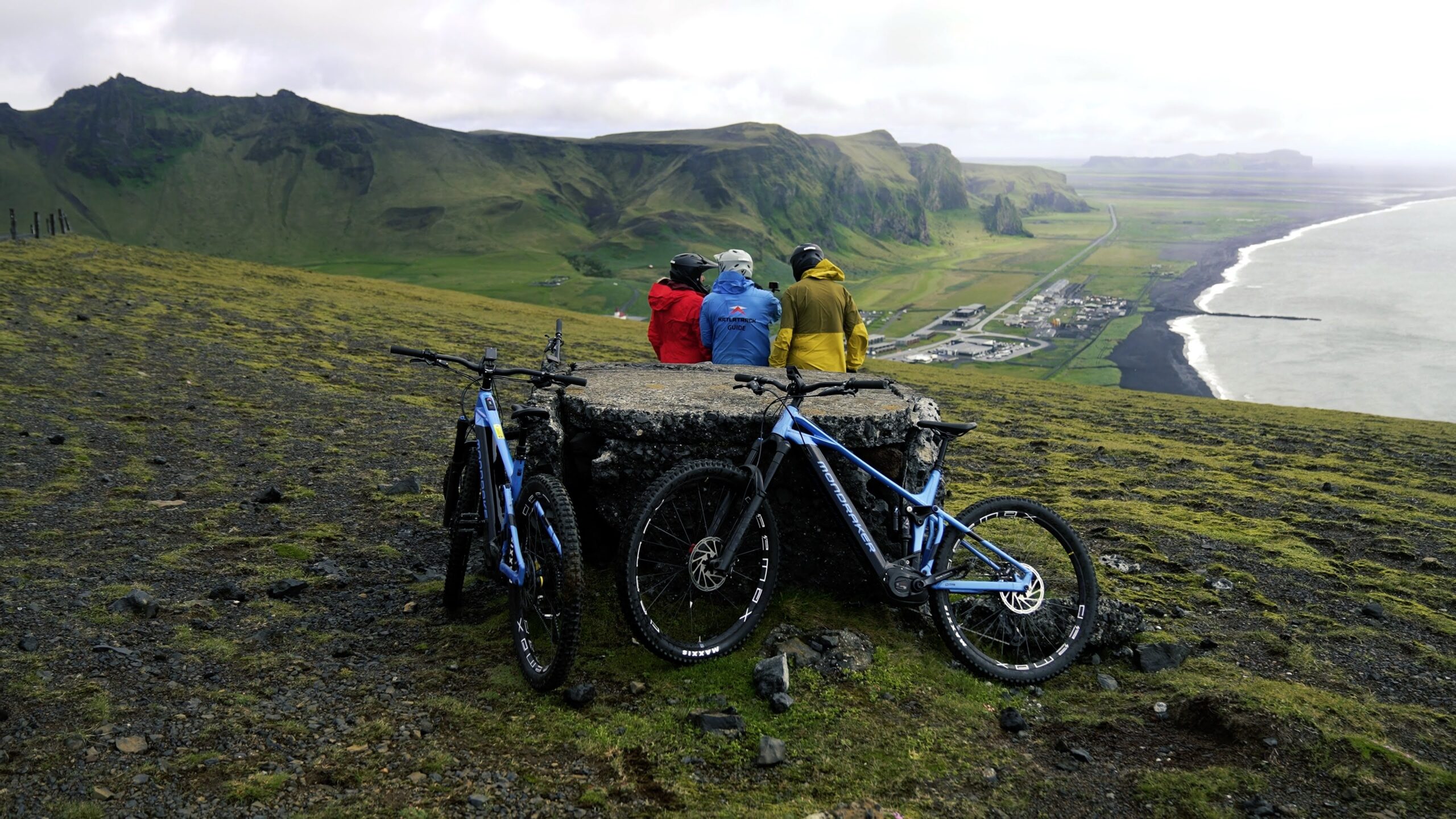 Electric mountain bikes and riders overlooking Vík from Reynisfjall
