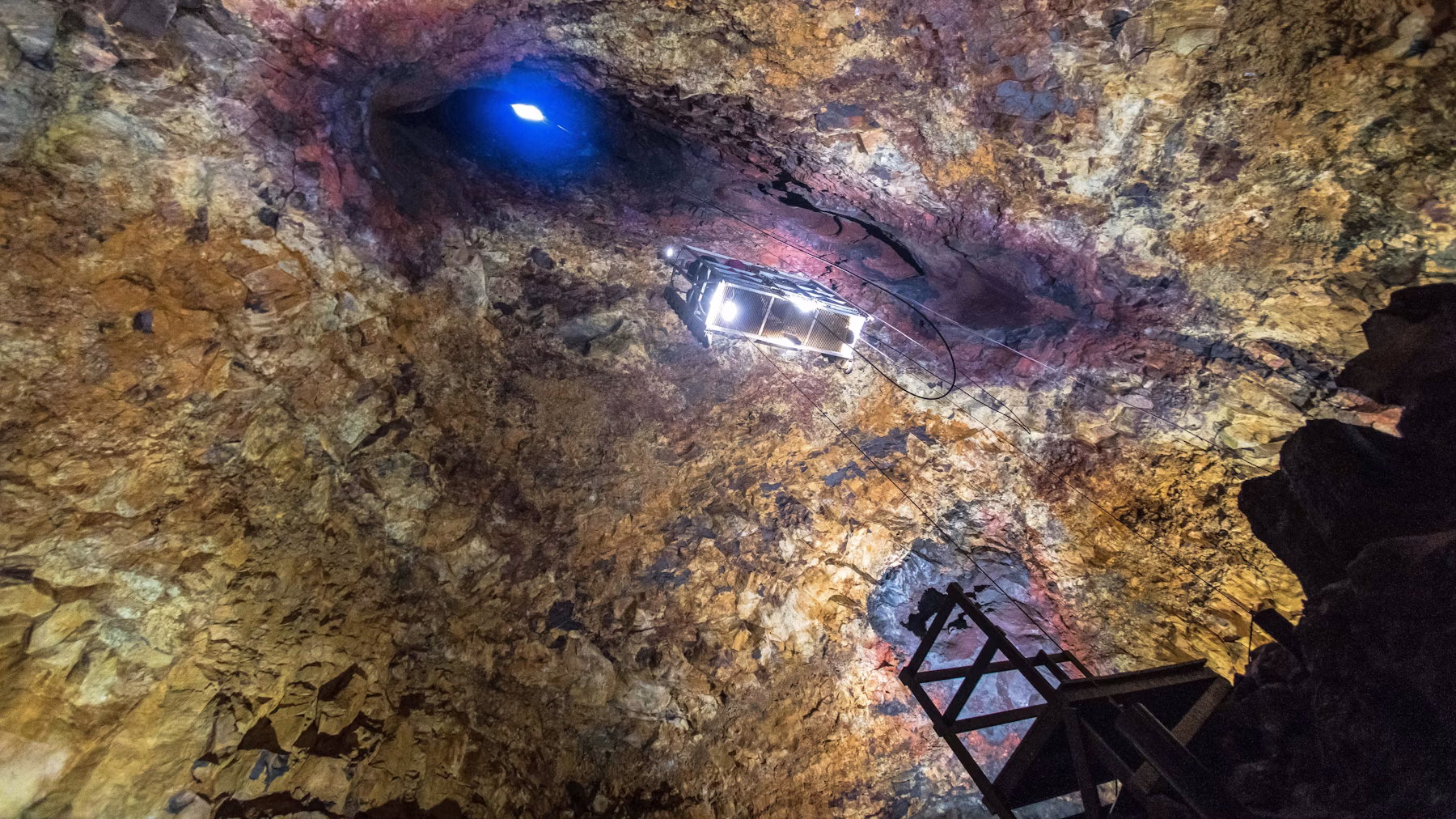 An open lift suspended below the skylight inside the colorful Þríhnúkagígur magma chamber.