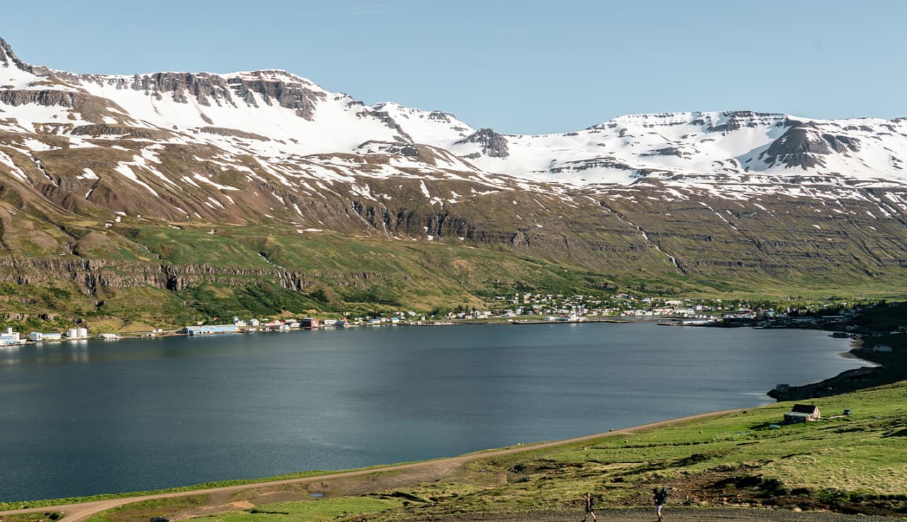 Seyðisfjörður town stretching along the inner fjord beneath snow-streaked East Iceland mountains