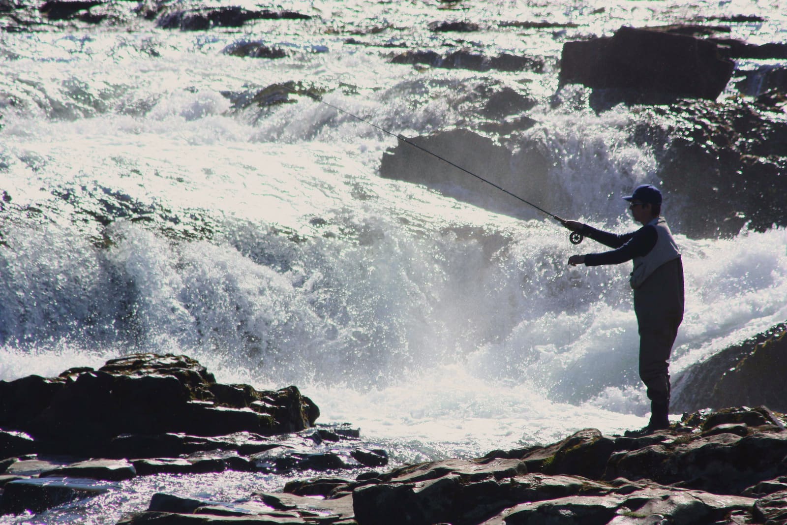 Angler casting a fly beside fast-running water on an Icelandic river