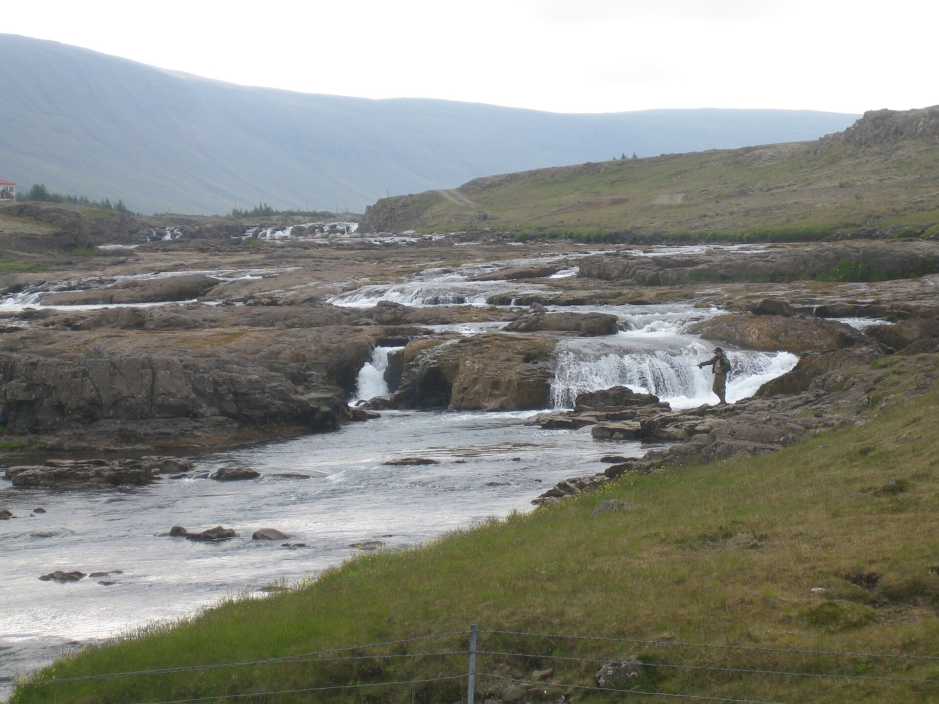 Angler beside stepped channels and small falls on Laxá í Hvalfirði