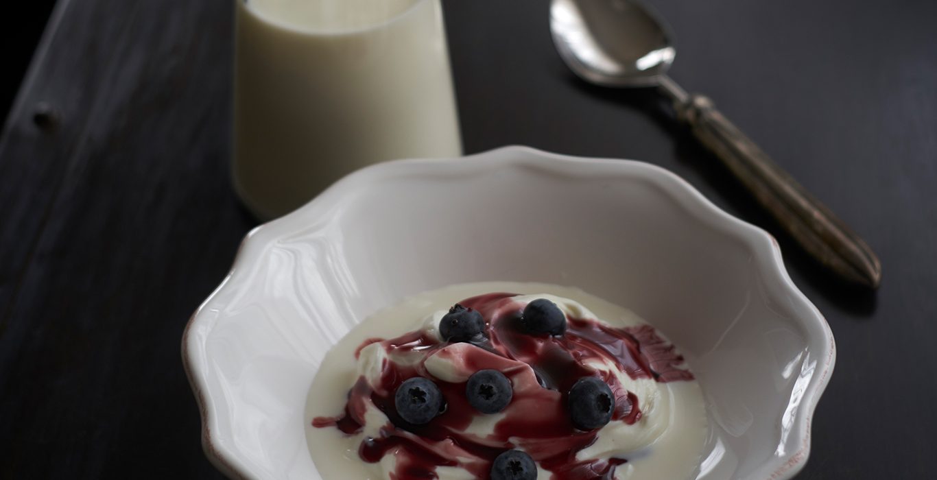 A bowl of skyr with berries and milk on a table