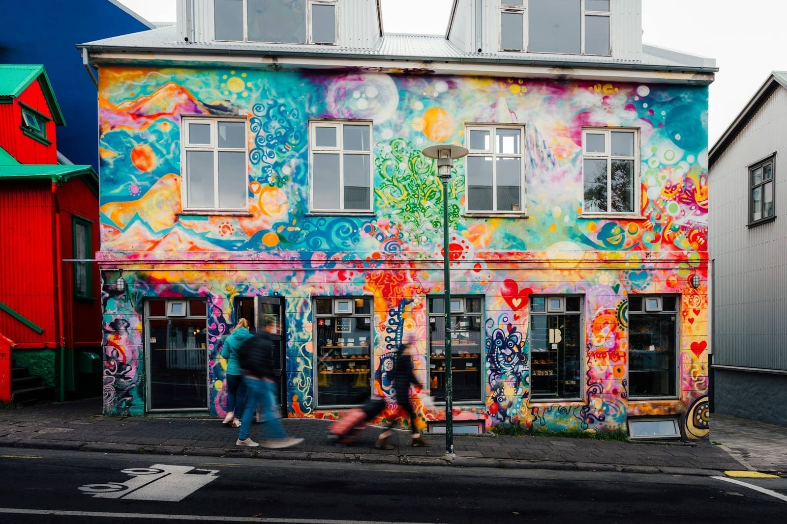 Pedestrians passing a colorful mural in central Reykjavík