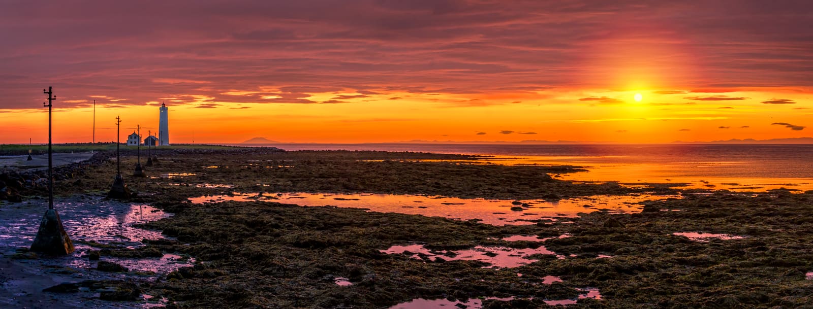 Low summer sun over the tidal shore and lighthouse at Grótta